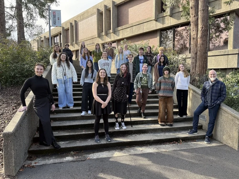 Photo of Terry Longshore and group of SOU Honors College students, outside the SOU Music Building on the steps. Posed casually and smiling.