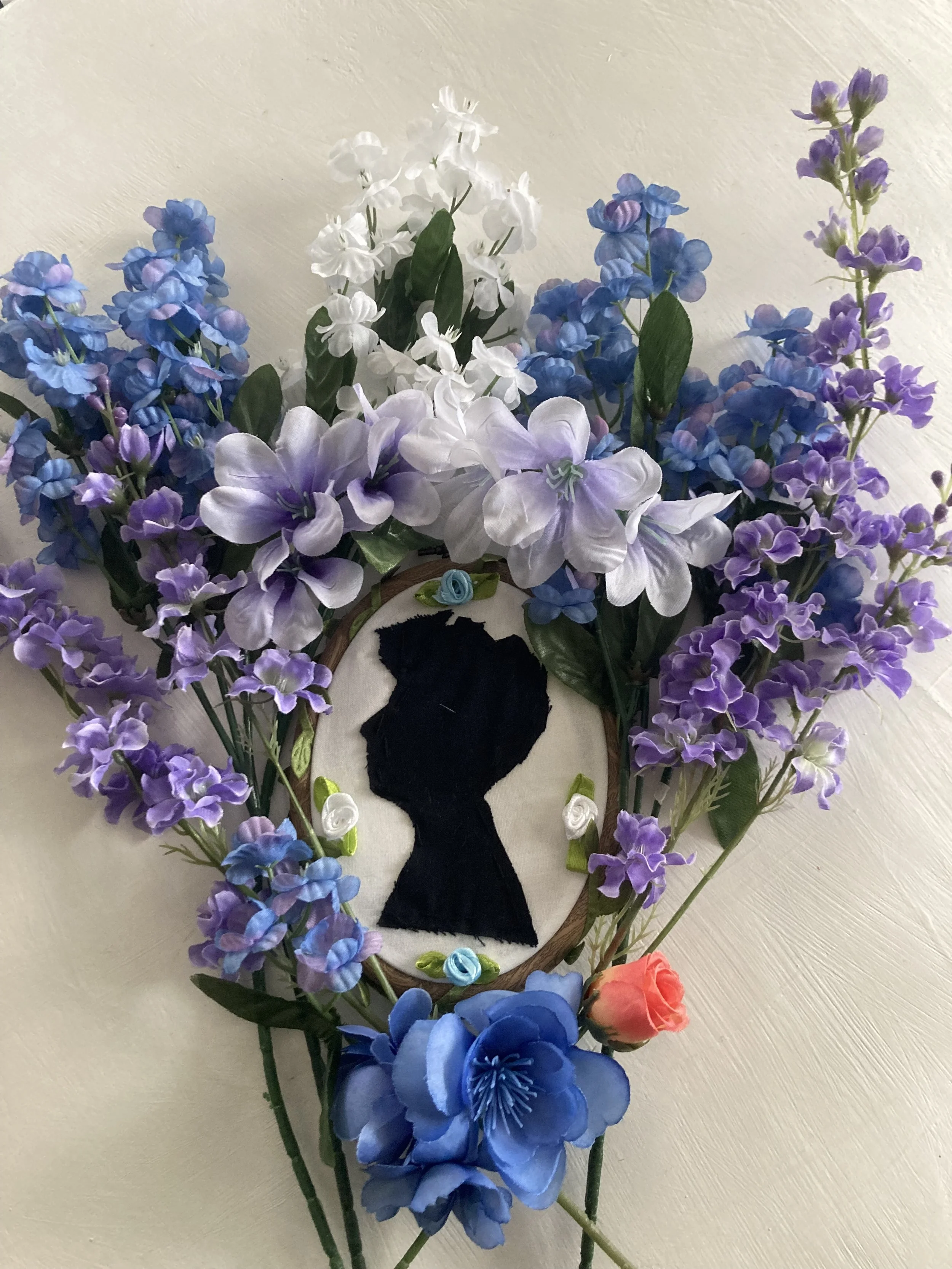 A cut-out silhouette surrounded by blue and purple flowers.