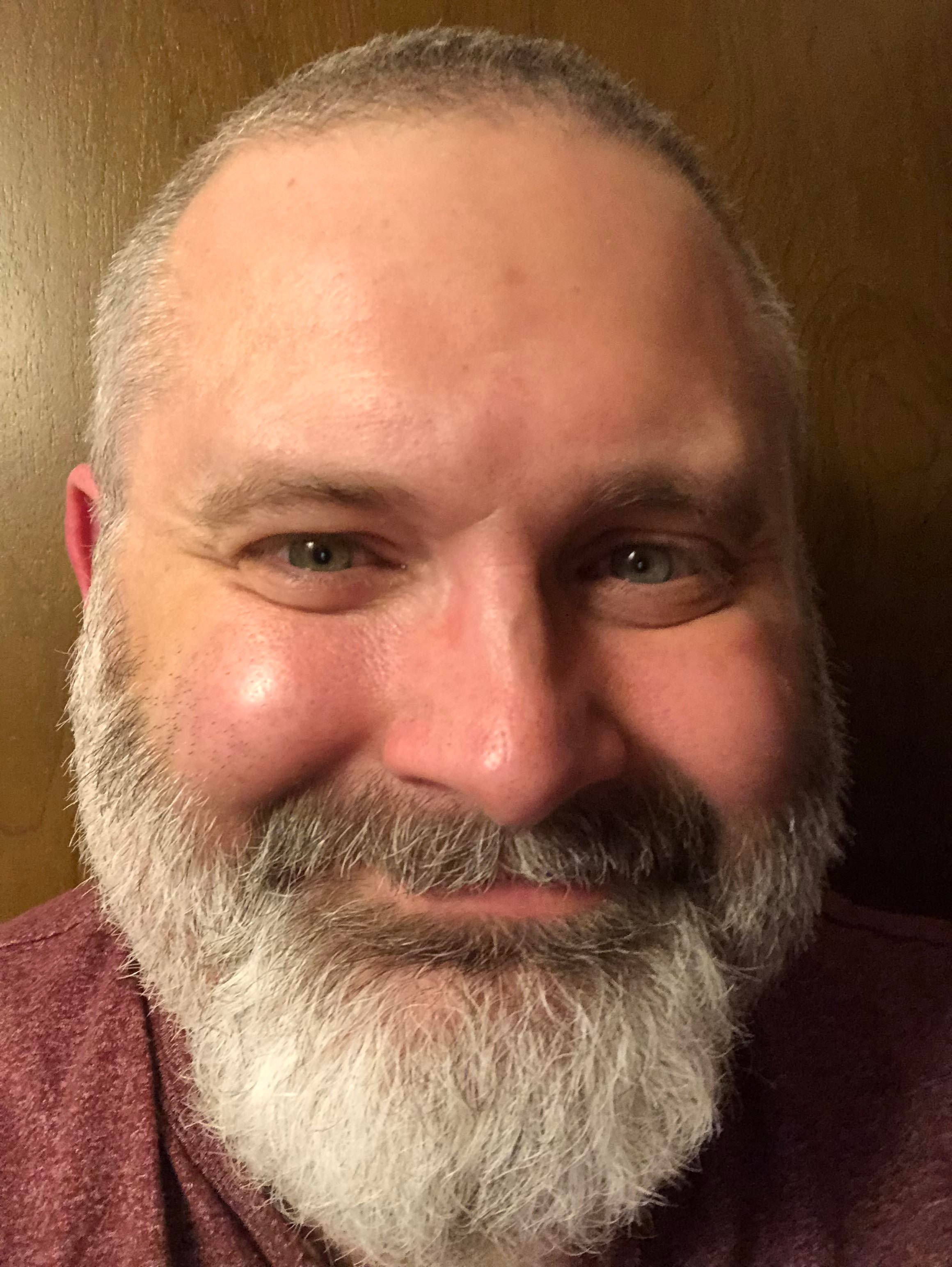 Jolly looking man with close-cropped hair and a grey and white beard.