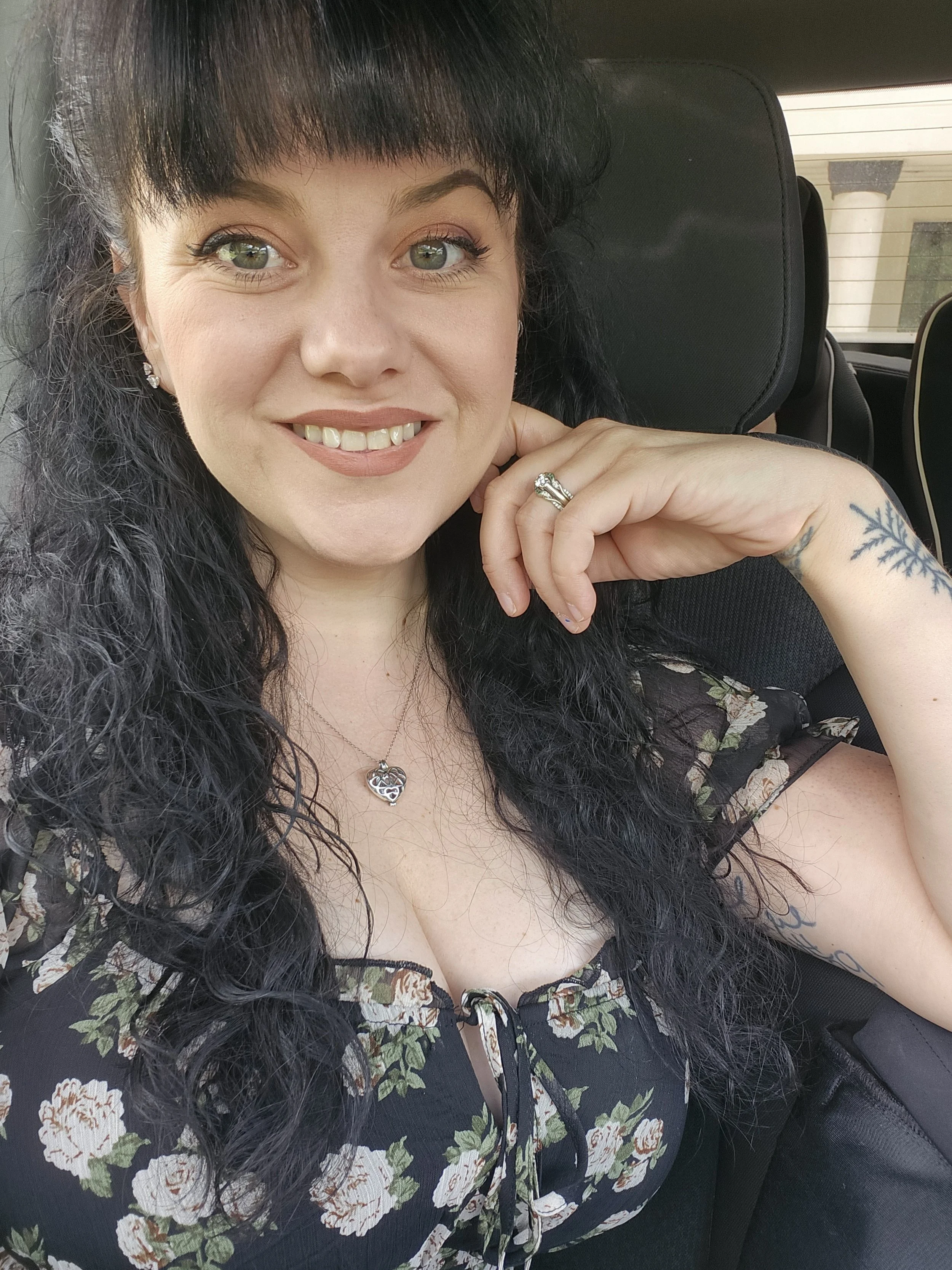 Image is of a smiling woman with dark hair wearing a floral dress.