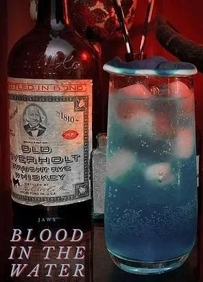 Image featuring a blue cocktail in a Collins glass with the name, "Blood in the Water" in the lower left.