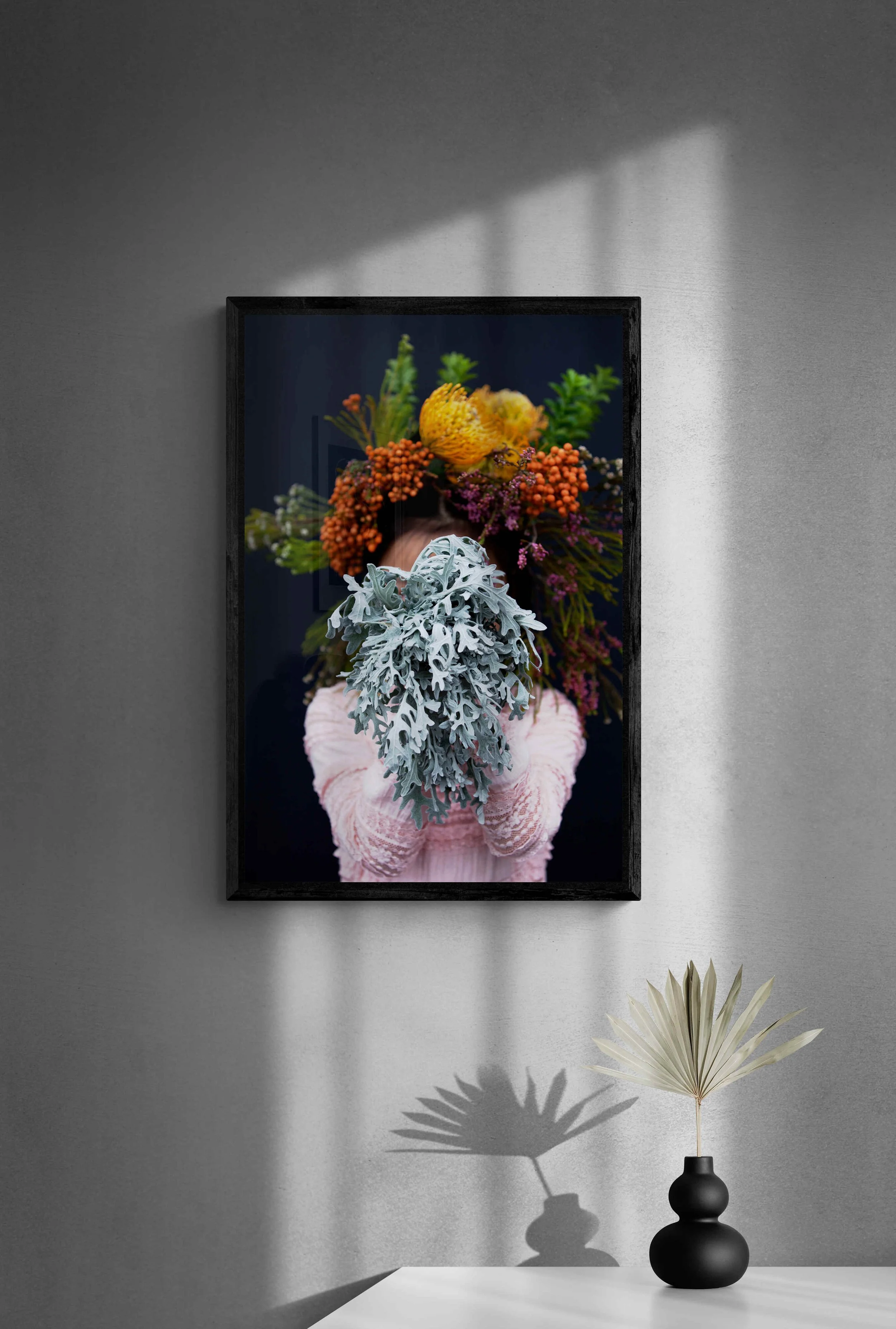 Black_vase_with_dried_leaves_on_white_table.jpg