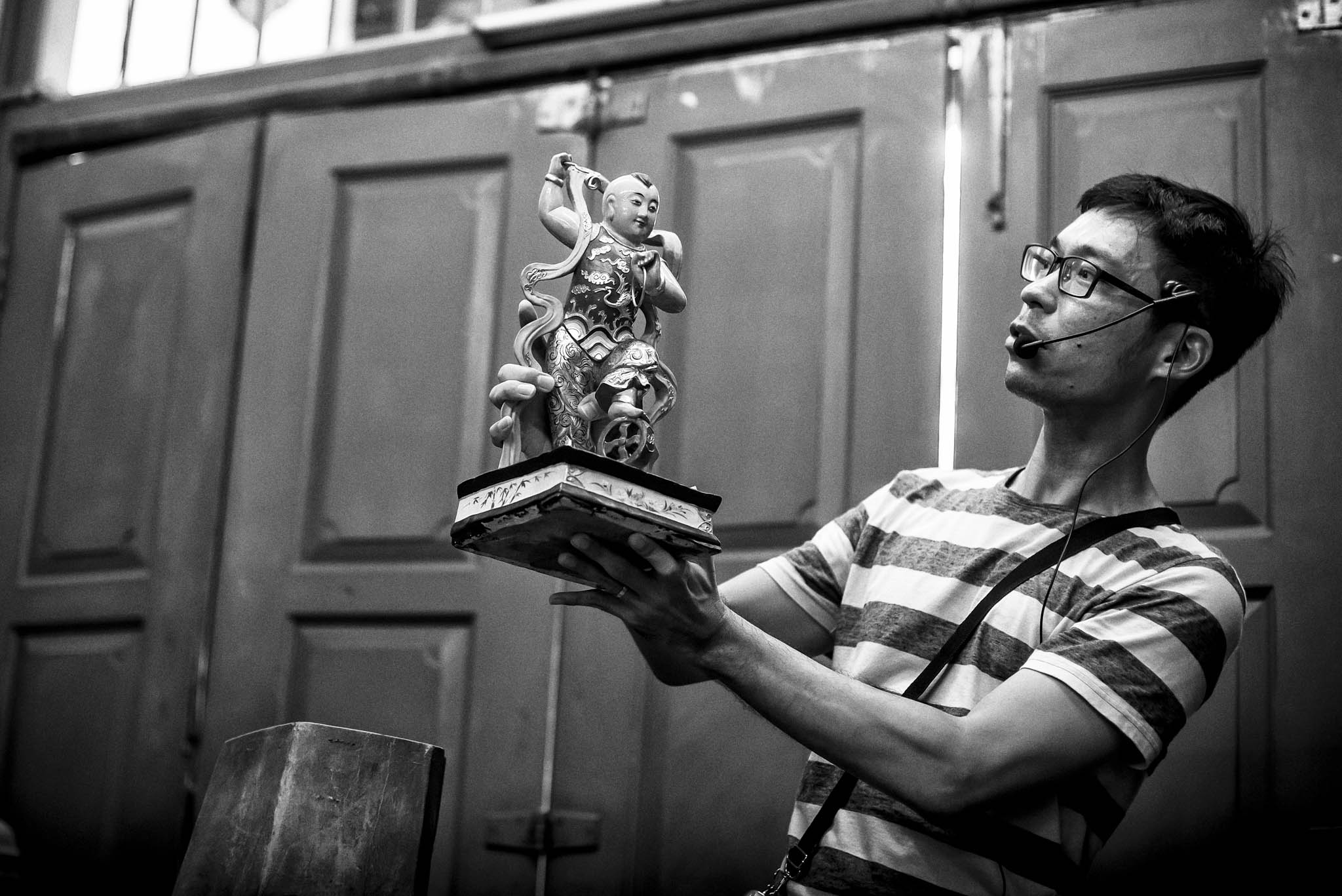 Mdm Tan’s grandson, Ng Tze Yong, 37, holds up the effigy of Ne Zha and tells the story behind the deity to an audience during an AirBNB tour.