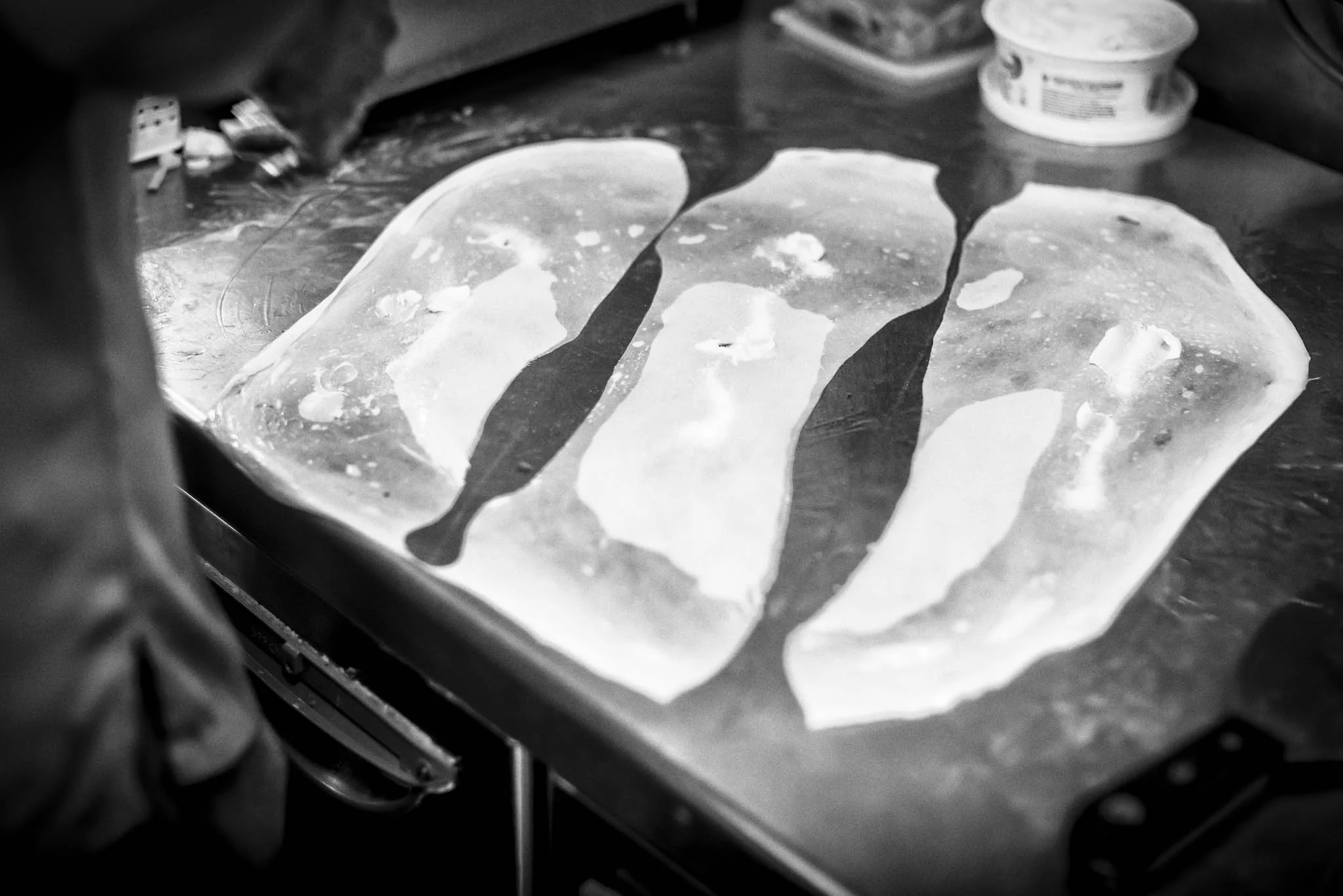 Making of the “coin prata” starts with splitting one dough ball into three thin slices.