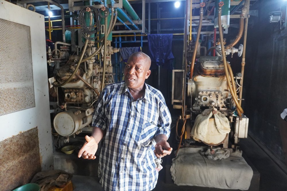  In the engine room, maintenance man Célestin Badarou explains how the compressors for the cold store (at a standstill) and the ice machine (currently operating) work. The cost of electricity for the compressor is 2.5 million CFA francs per month (ar
