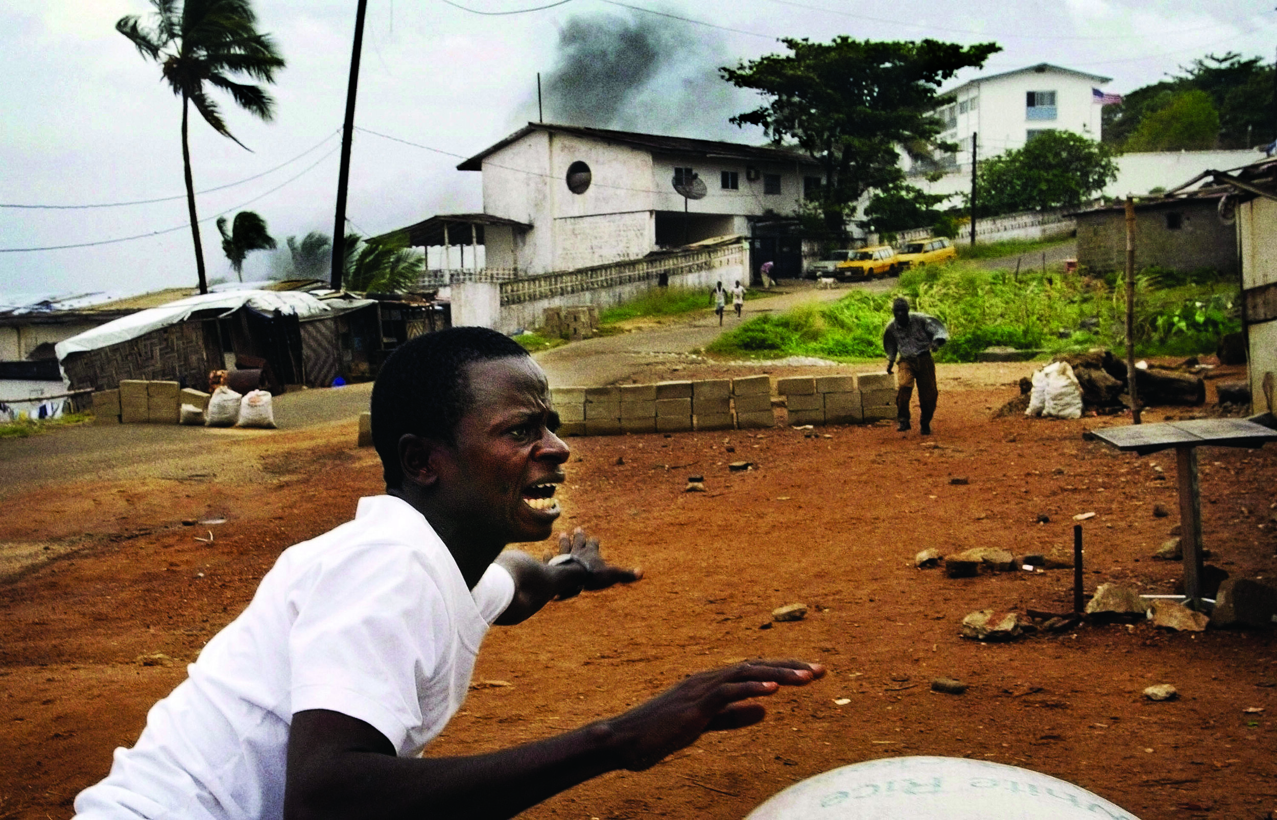  Liberians scatter in fear as a mortar shell explodes near them (background) on July 21, 2003, in Monrovia. © Chris Hondros/Getty Images 