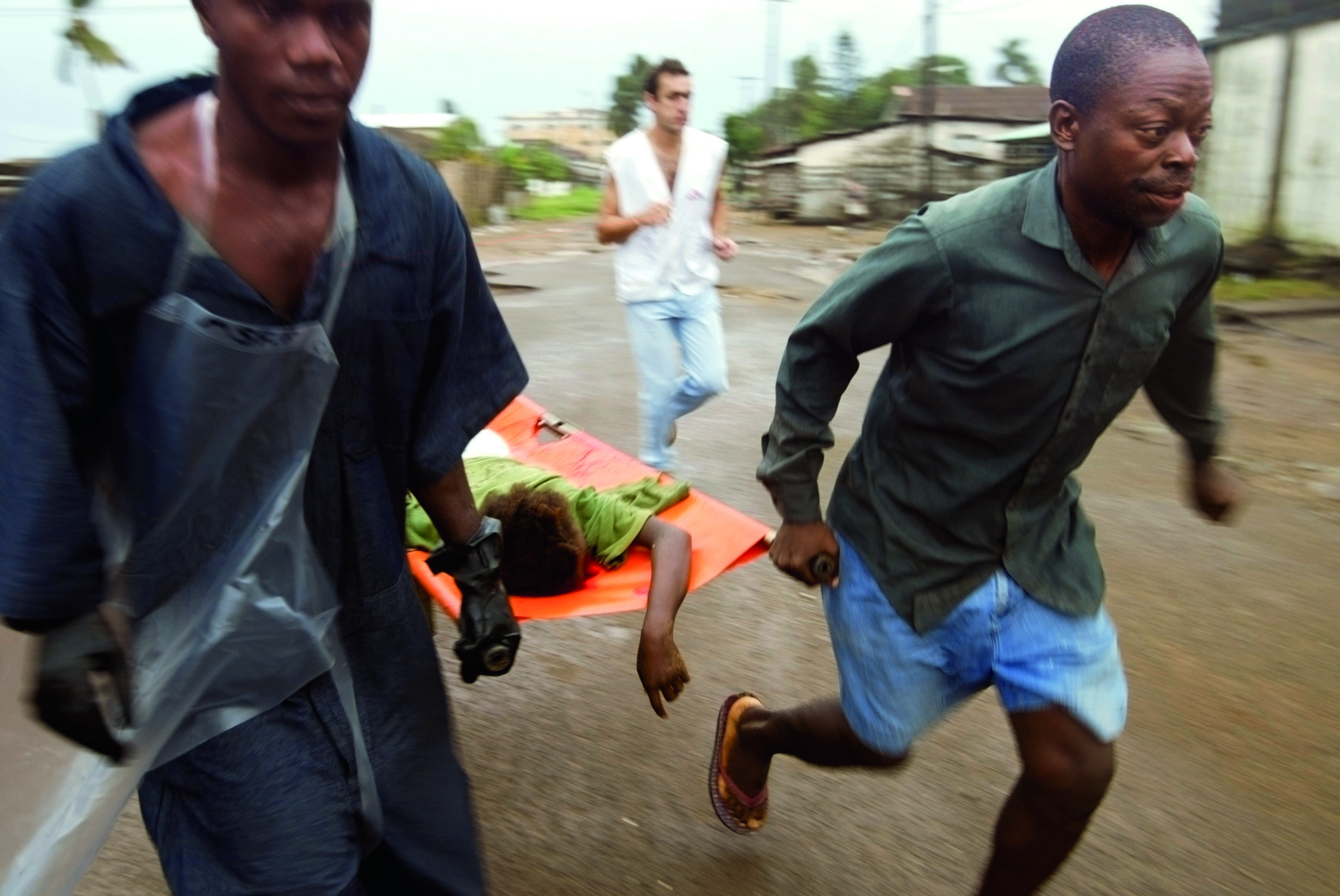  Aid workers with Doctors Without Borders rush an injured girl to a clinic minutes after a shelling attack on July 25, 2003, in Monrovia. © Chris Hondros/Getty Images 