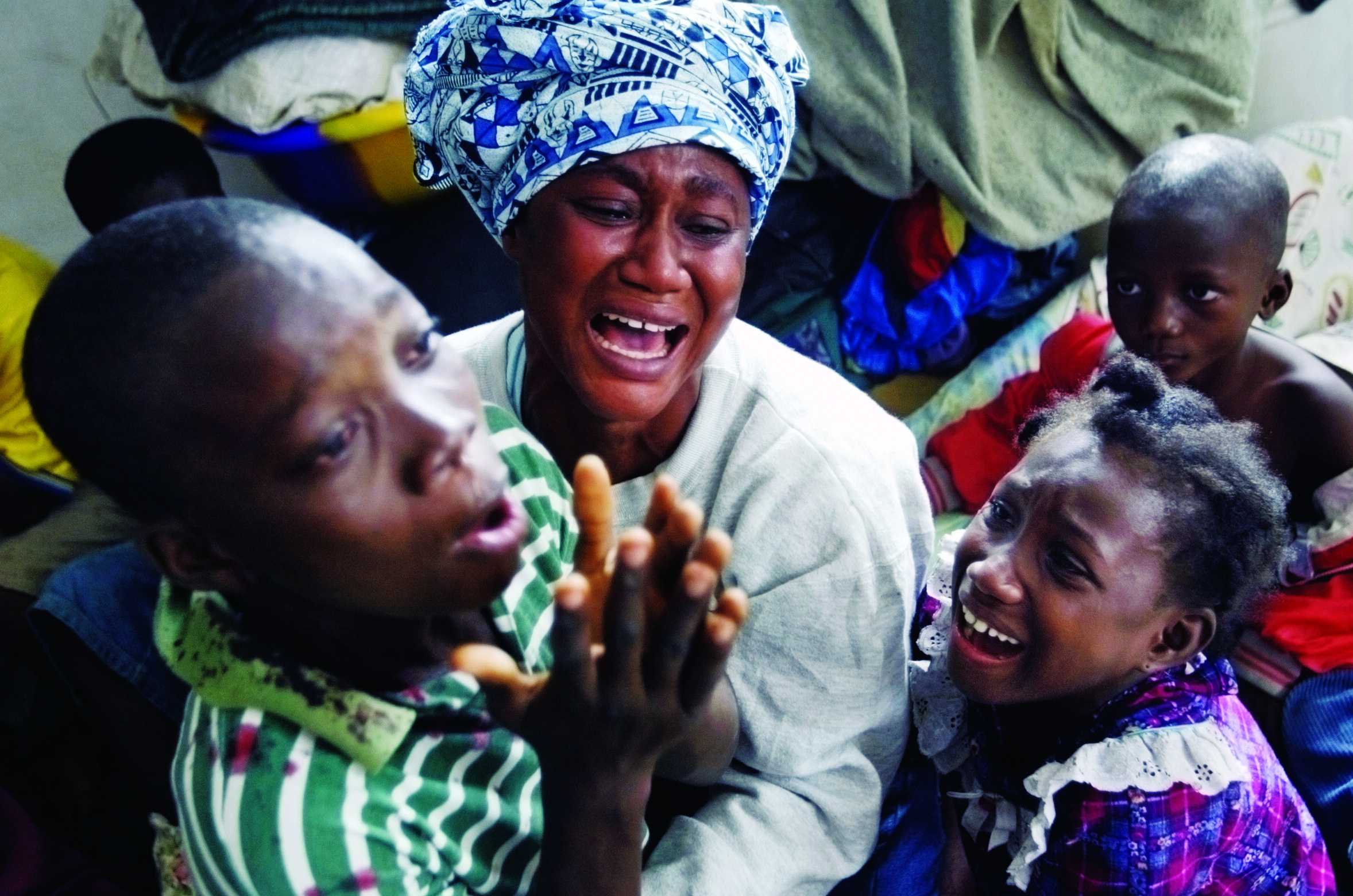  Relatives of refugees who had been killed minutes before by mortar shells grieve on July 21, 2003, while they huddle in their makeshift refugee camp at a small school in Monrovia. © Chris Hondros/Getty Images 