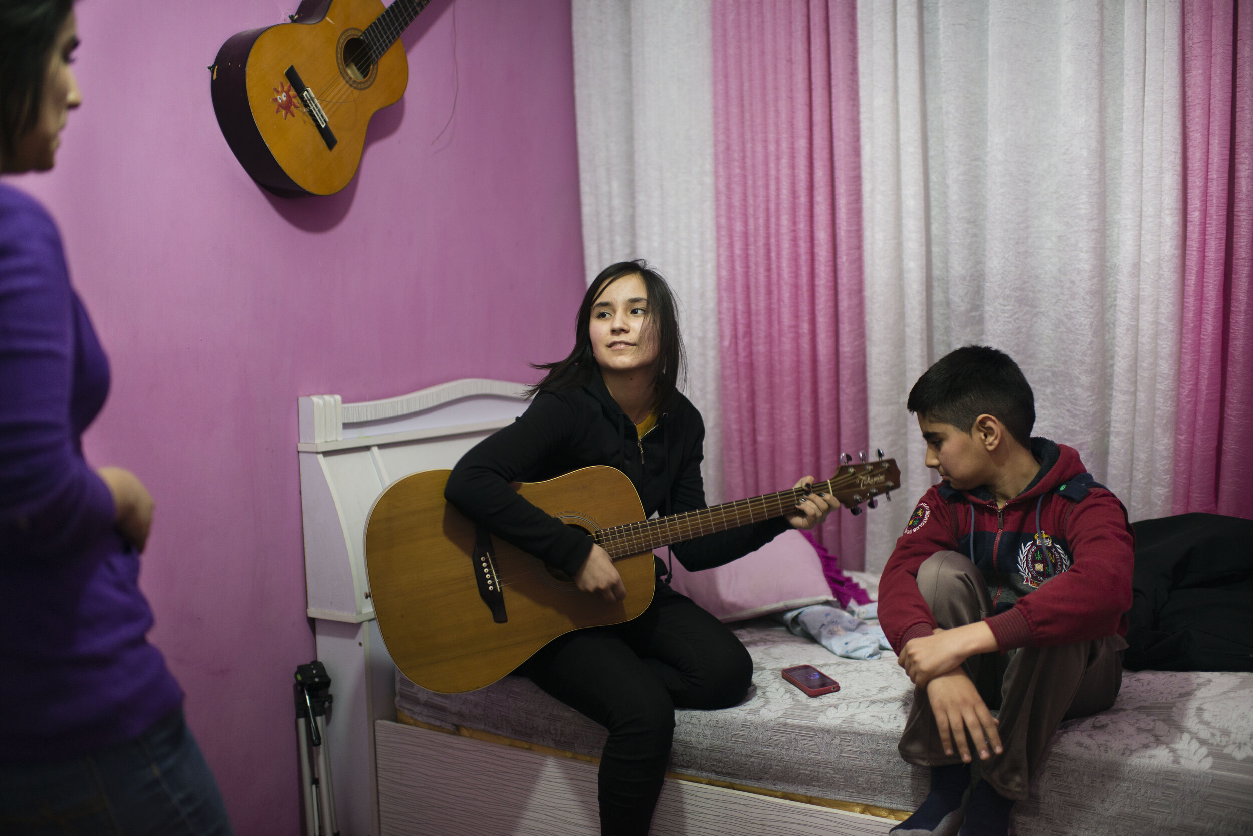  Zhala, age 16, plays a cover of an Avril Lavigne song as her brother and sister sing along in Kabul (2015). © Kiana Hayeri  