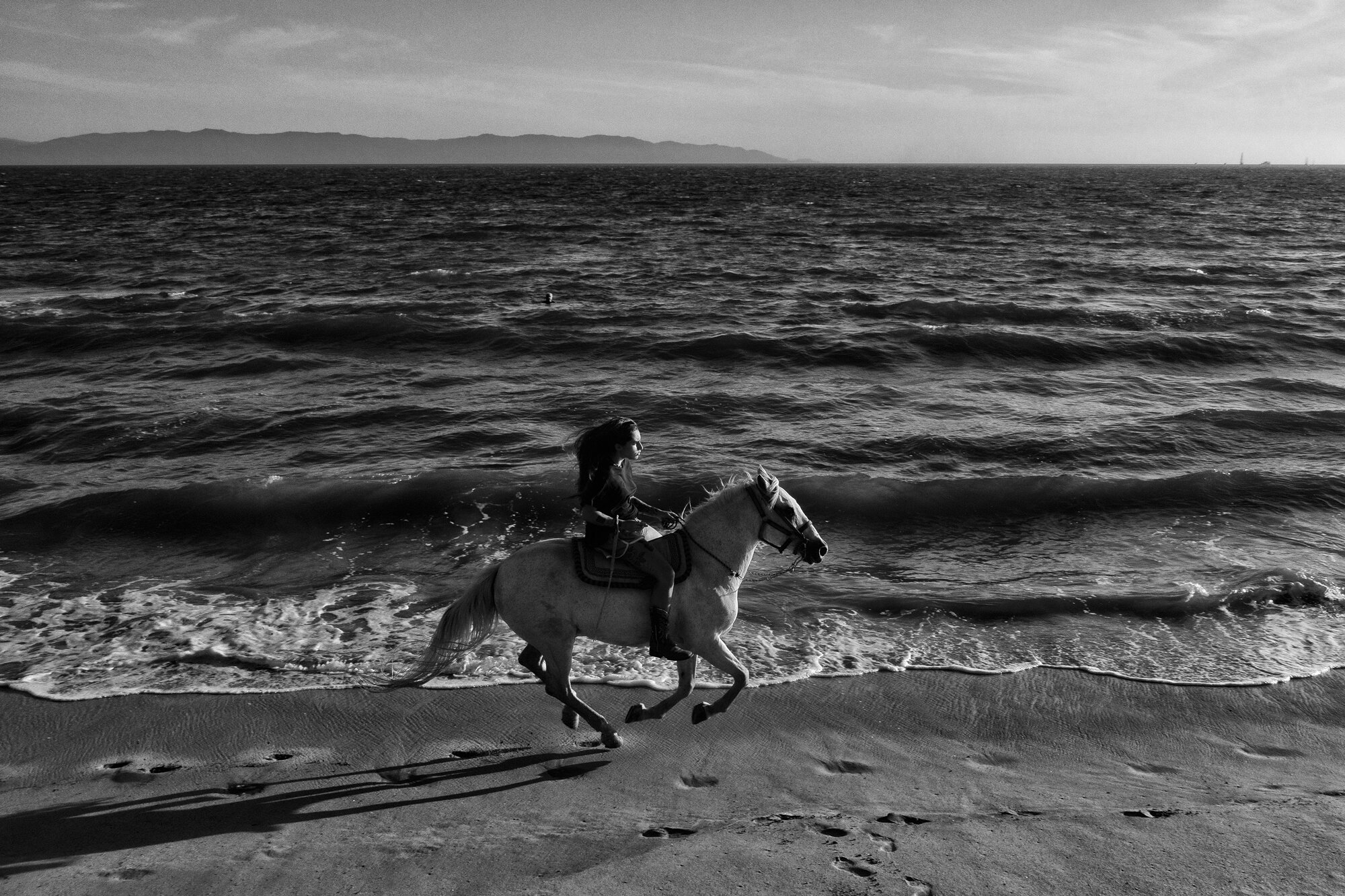  A woman rides a horse at Bucerias Beach. I walked to the beach to reflect, and to find others who go to the beach for peace and calm when she passed by me. The wind was against her so I couldn’t hear the steps of the horse. She appeared quickly and 
