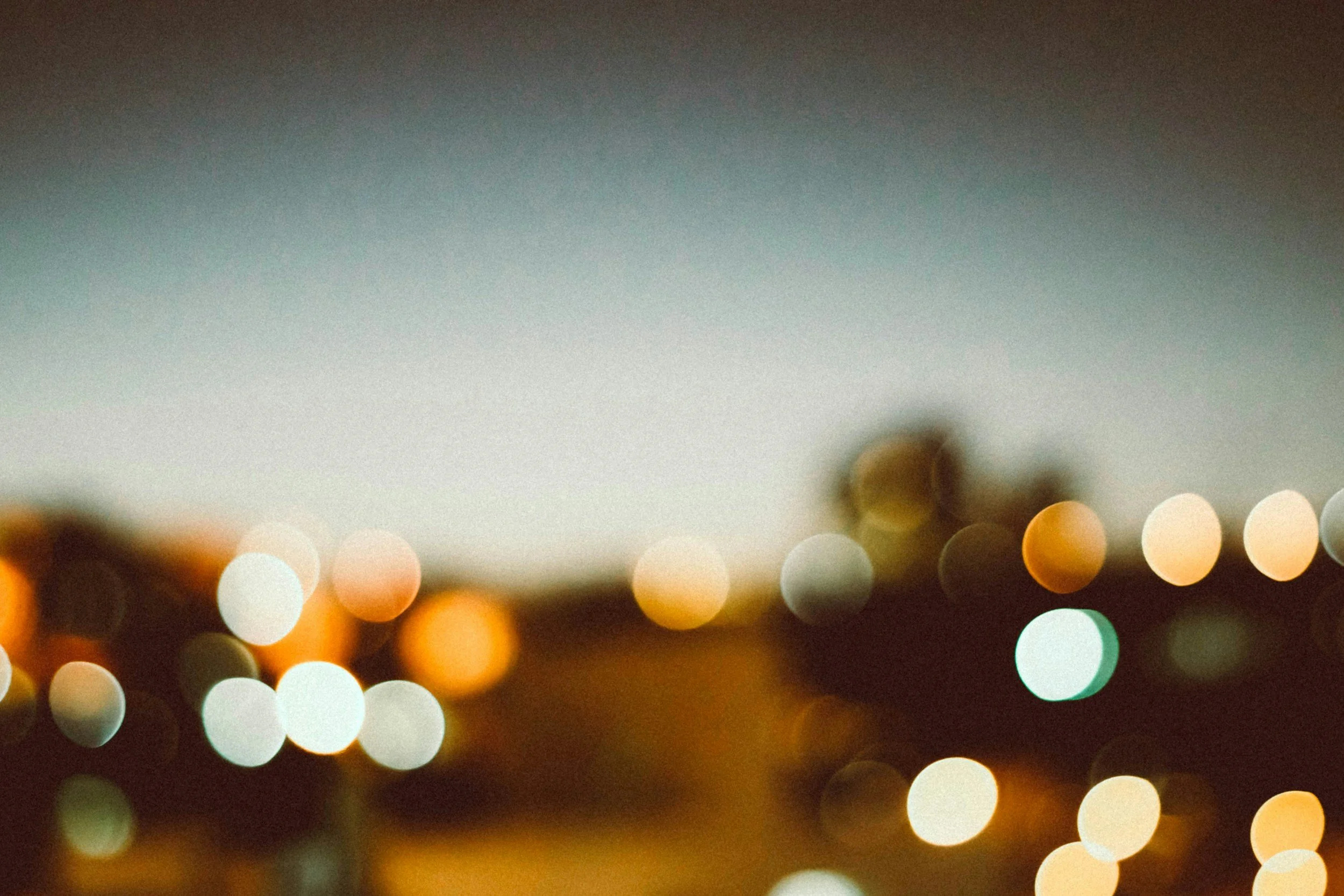 Blurred city lights at dusk with out-of-focus effect and a darkening sky.