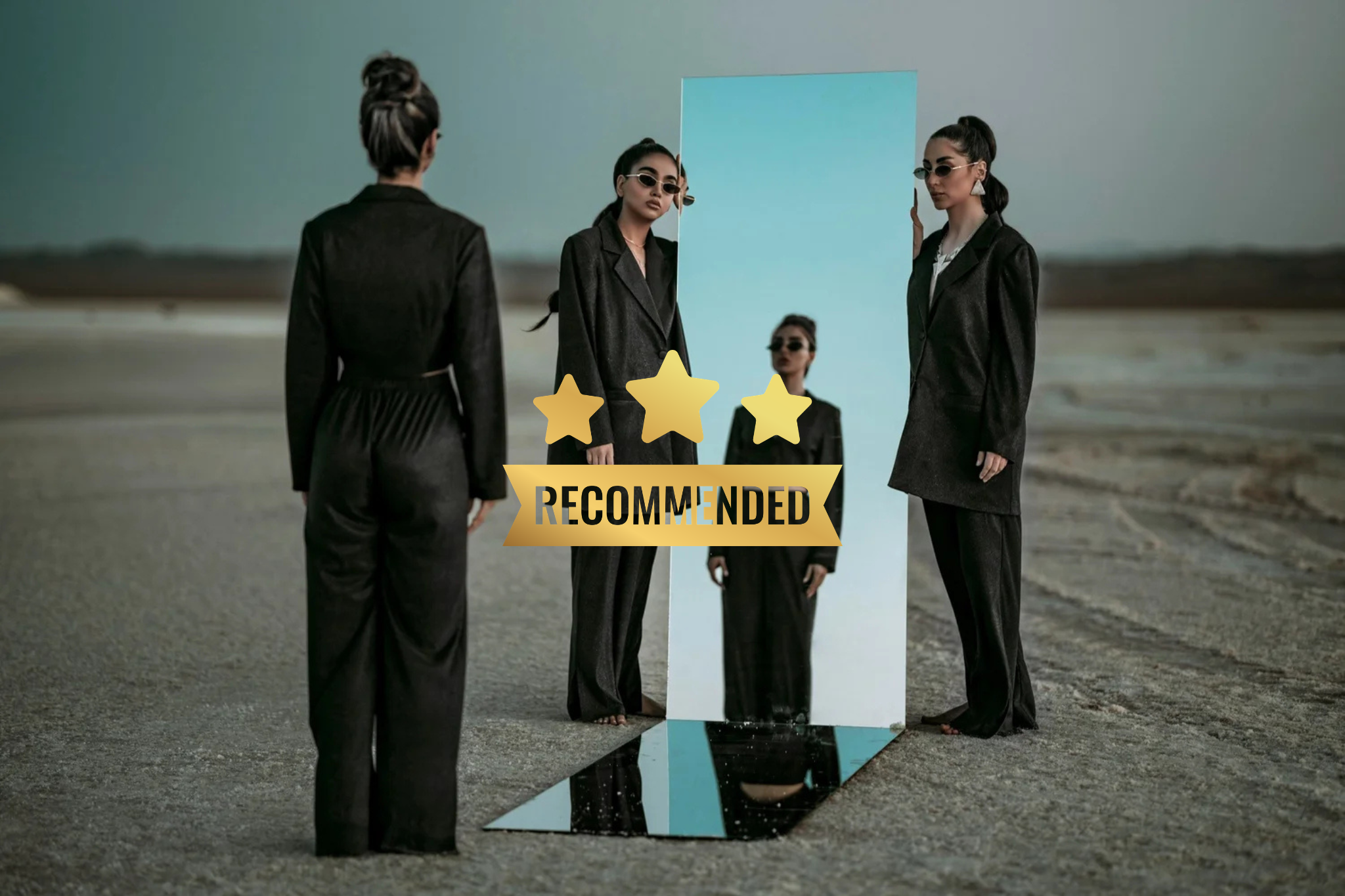 Four women in black suits standing on a gravel surface in front of a large mirror outdoors, with a "Recommended" badge featuring three gold stars overlayed on the image.
