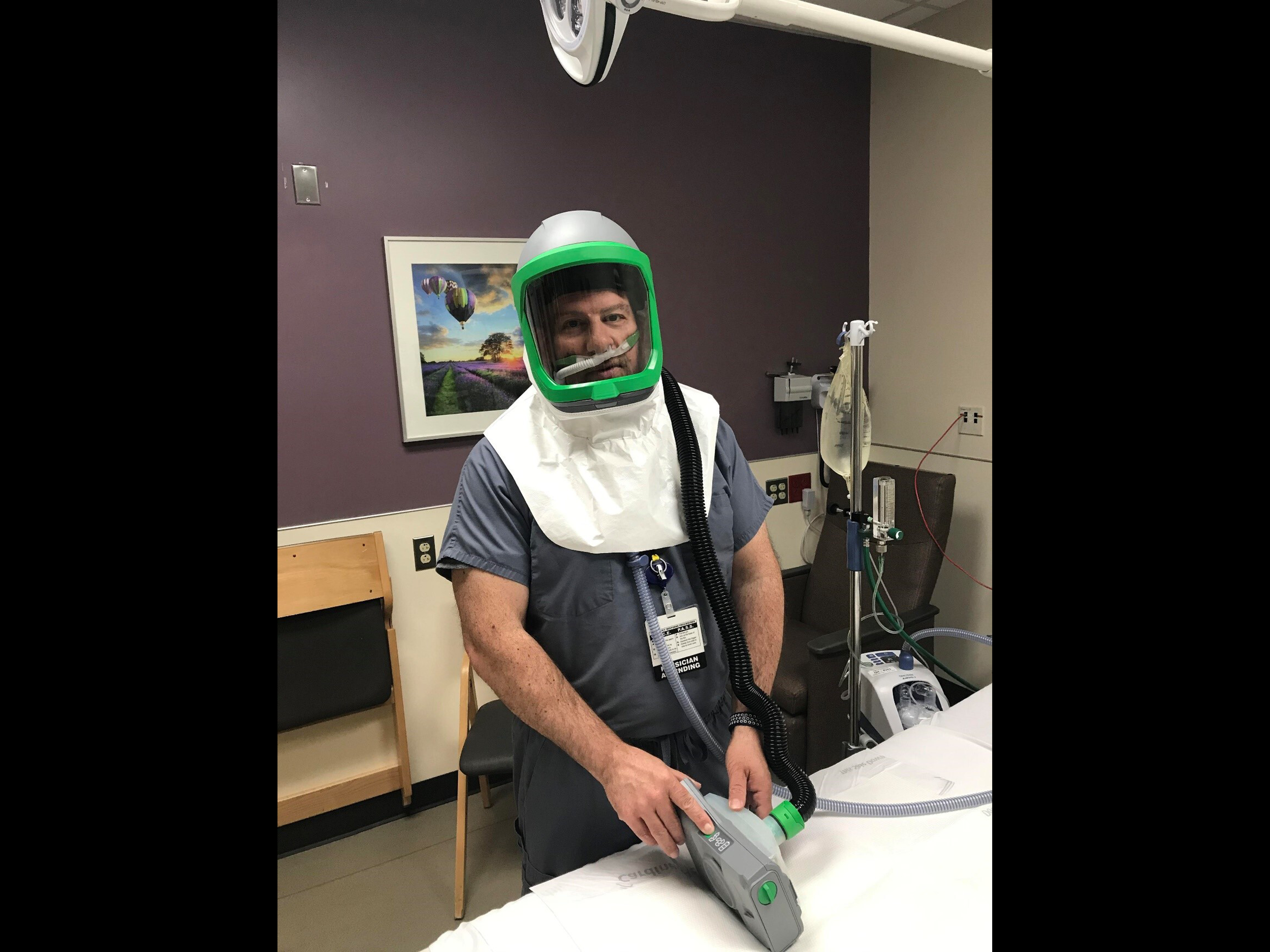  Healthy volunteer wearing the portable helmet negative pressure environment while on heated high flow nasal cannula, with HEPA filter and exhaust unit near bottom of image. The system draws oxygen, as well as room air, into the helmet, while pulling