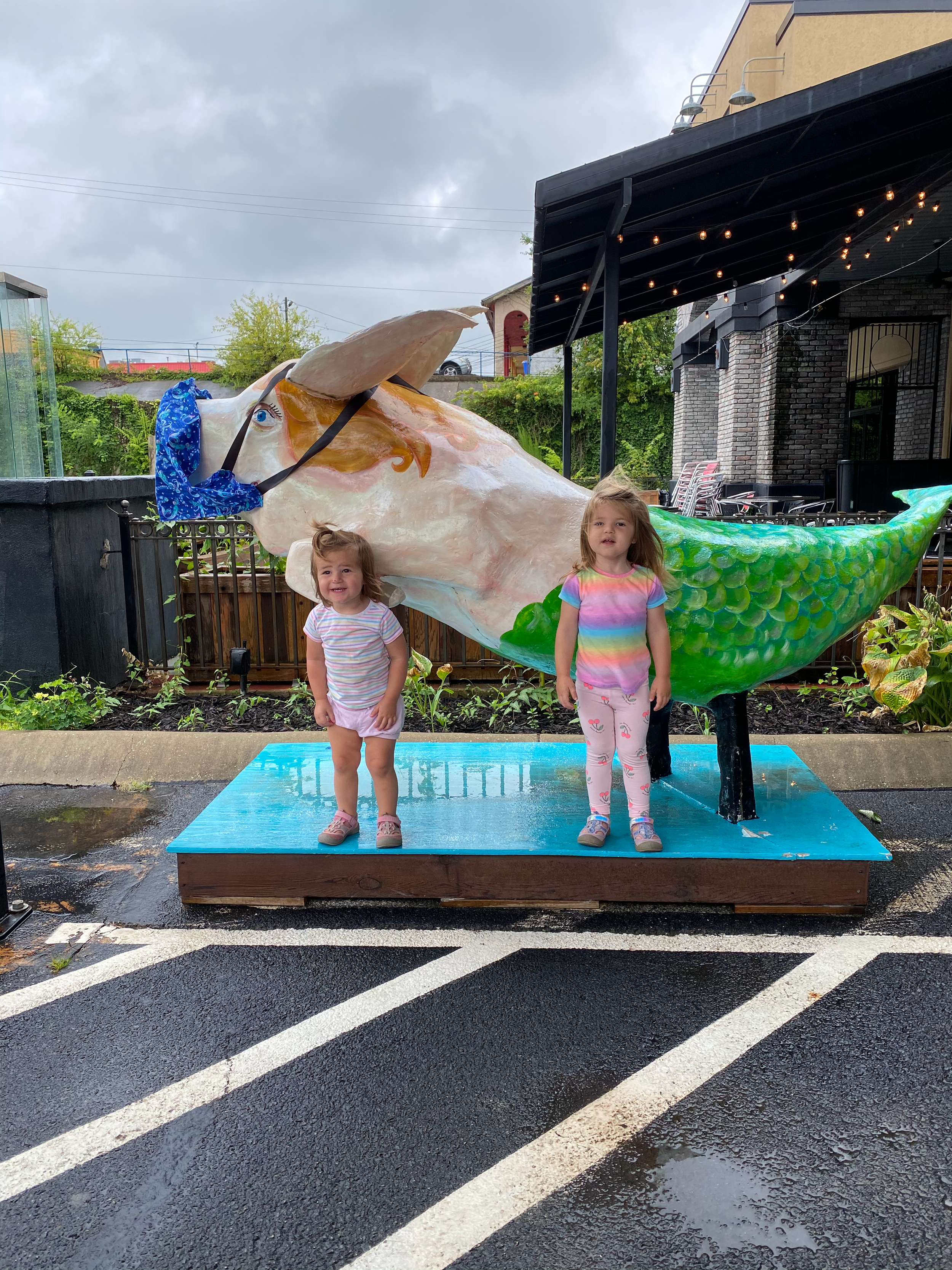 Two little girls stand in front of "Priscilla" pig at Mermaids Seafood Restaurant