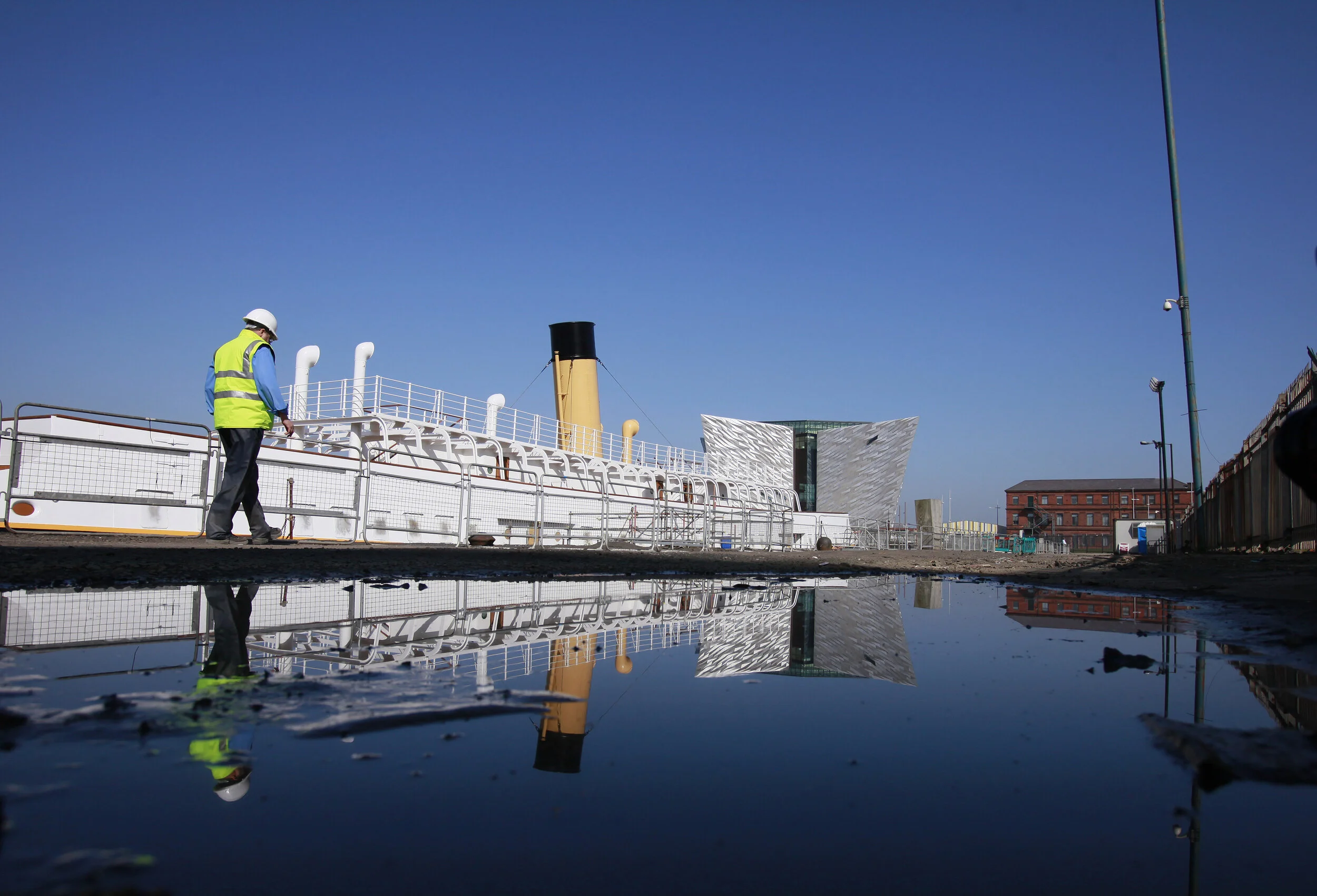  A worker walks along the dock of the ship Nomadic as the new Titanic building is seen in the background in the "Titanic Quarter" in Belfast, Northern Ireland. A century after the Titanic sank on its maiden voyage, Belfast is counting on a new visito