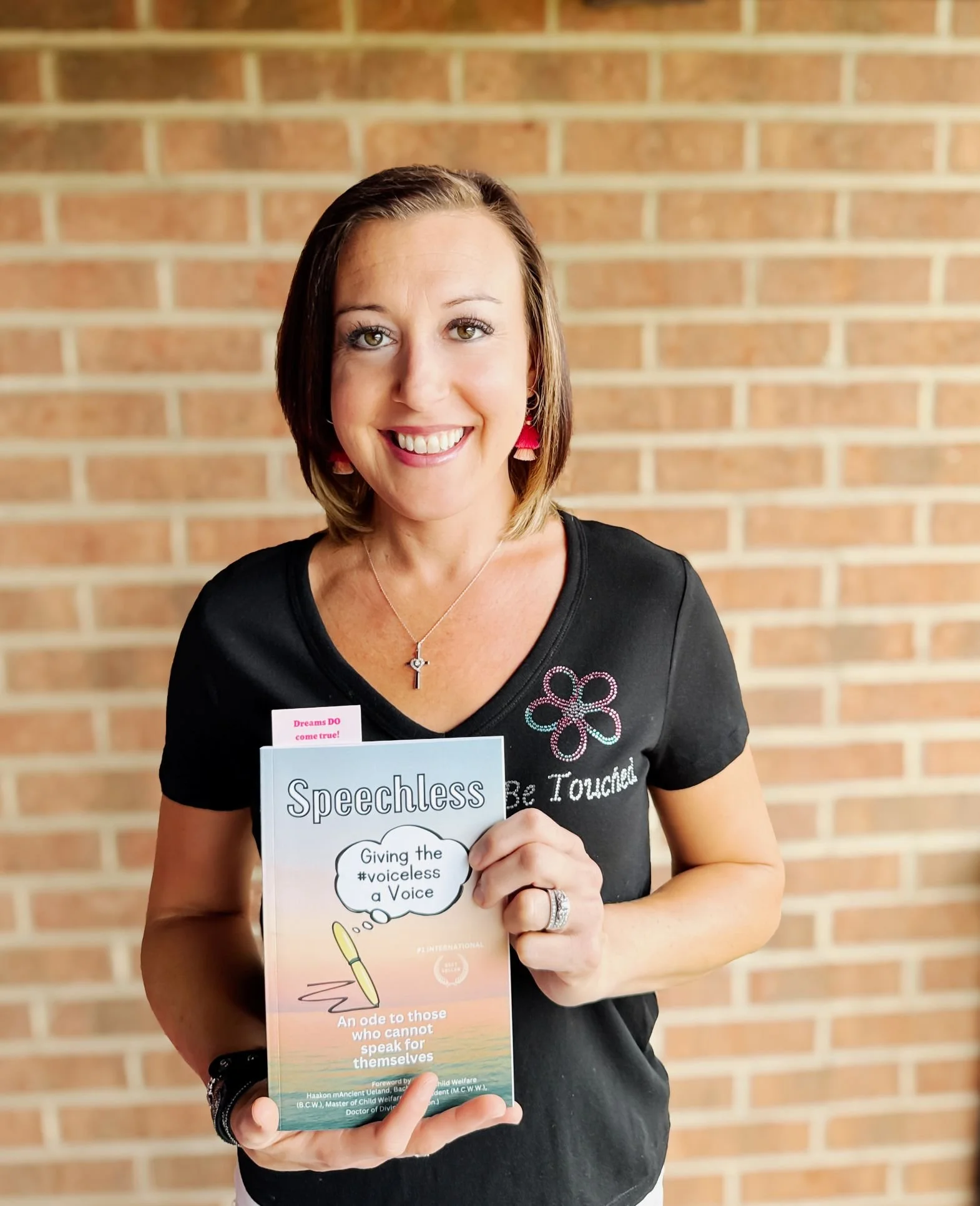 Chicago author Sabrina Schottenhamel holding copy of co-authored book Speechless Give the #voiceless a Voice