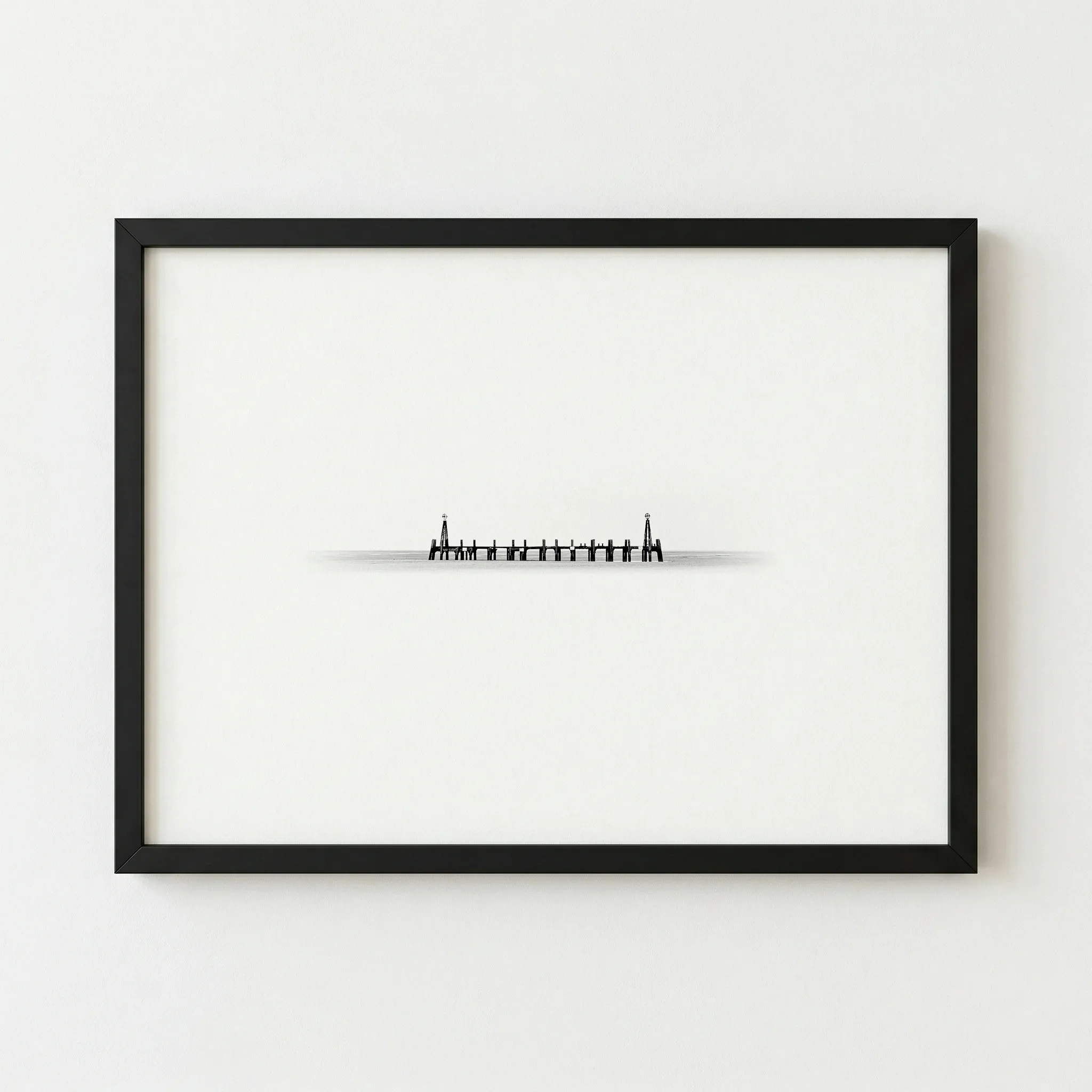 The 'Distance & Isolation' pier print in a black wooden frame, providing a sharp, graphic border.