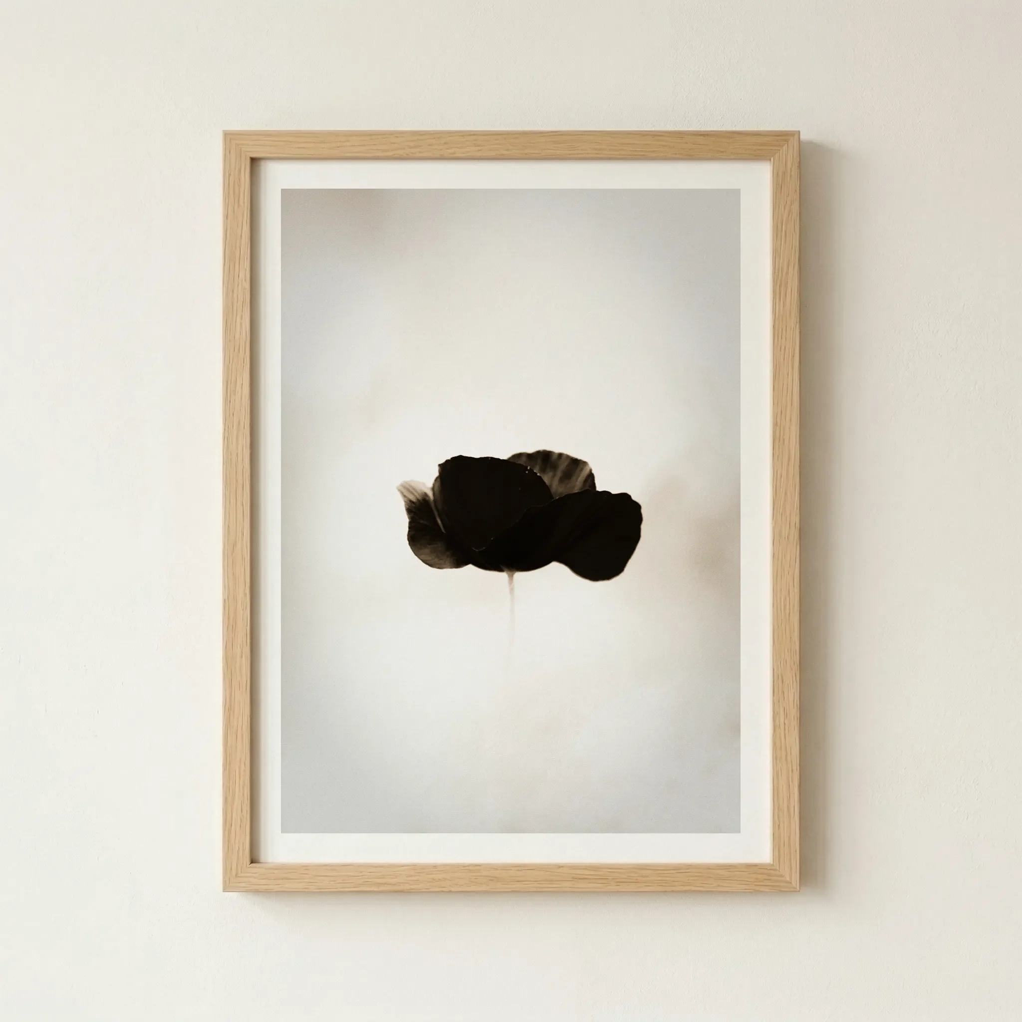 Black Poppy minimalist art in a natural wood frame, adding organic warmth and a Japandi aesthetic to the monochrome botanical composition.