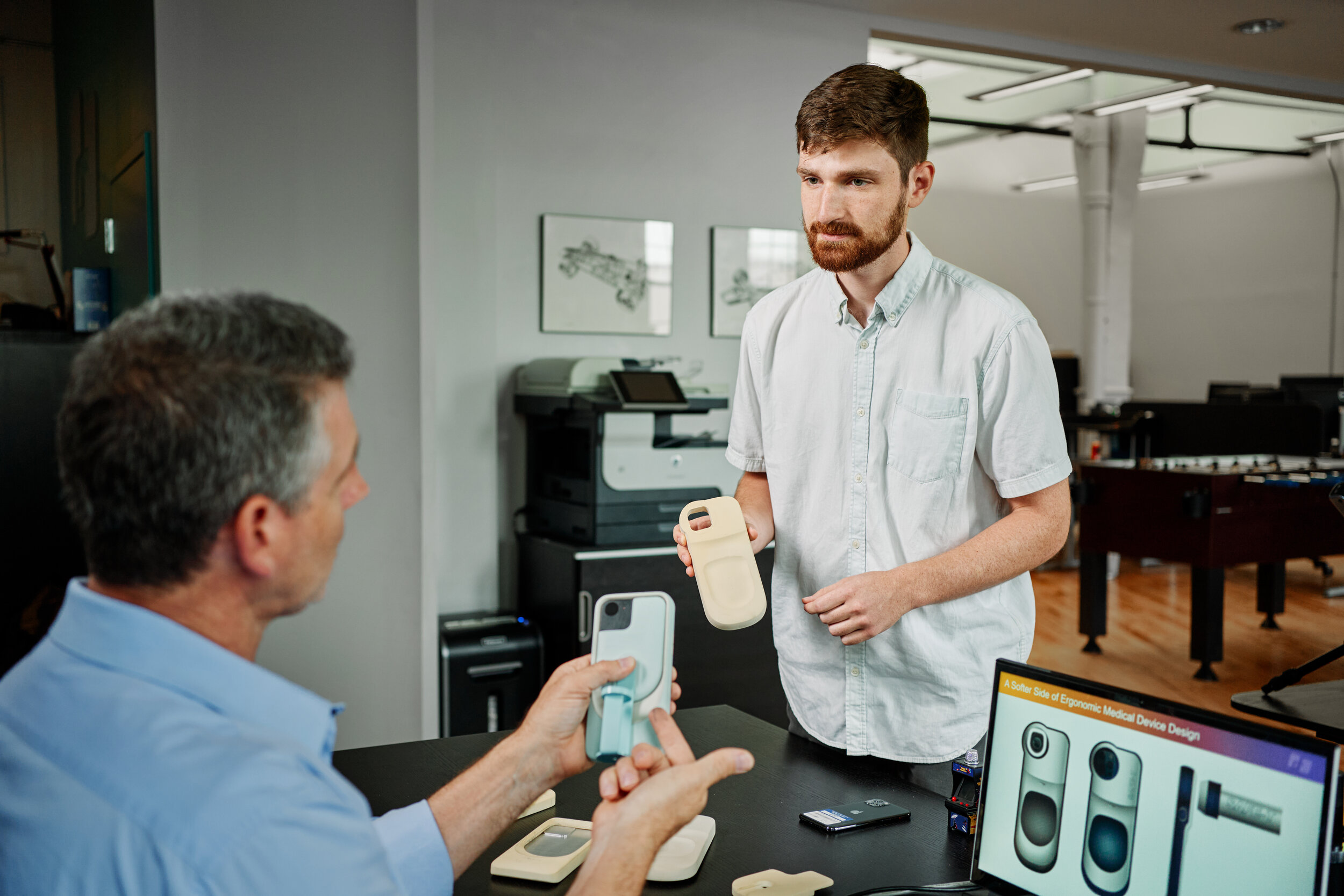  Industrial designers discuss the ergonomics of a foam model for a phone cover used in a medical setting 