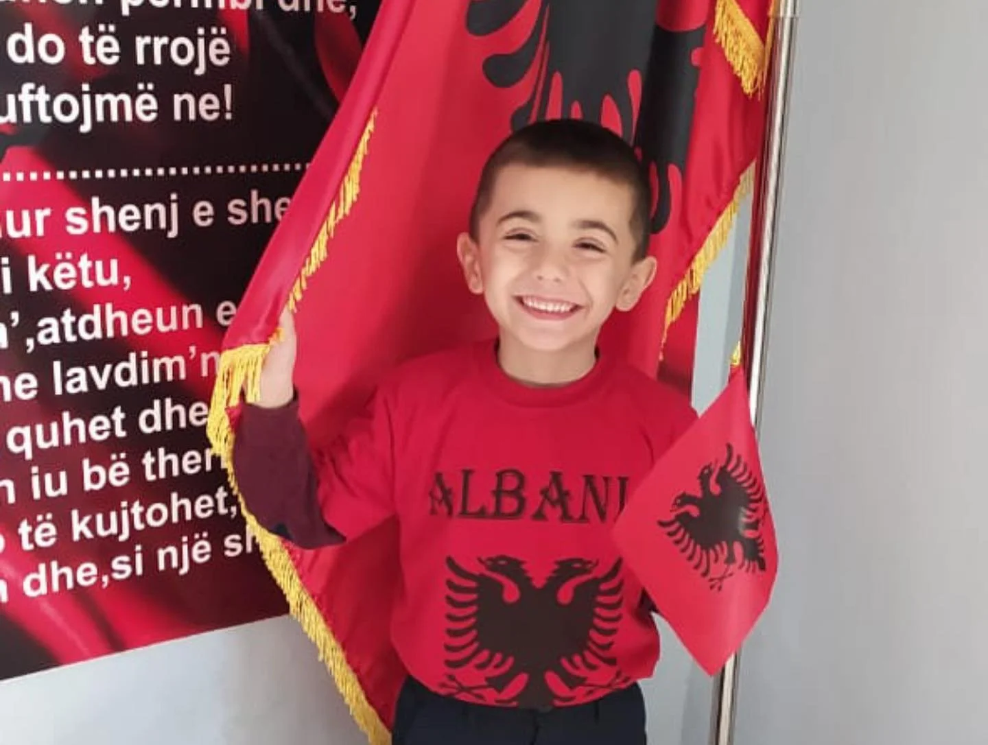 Smiling child holding Albanian flags