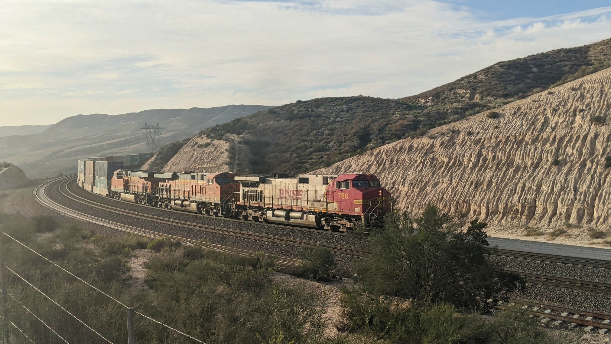  A BNSF train, led by a locomotive in the Santa Fe’s “Warbonnet” livery, crests Cajon Pass in the late afternoon. Photo by Alex Lewis, 2021.  