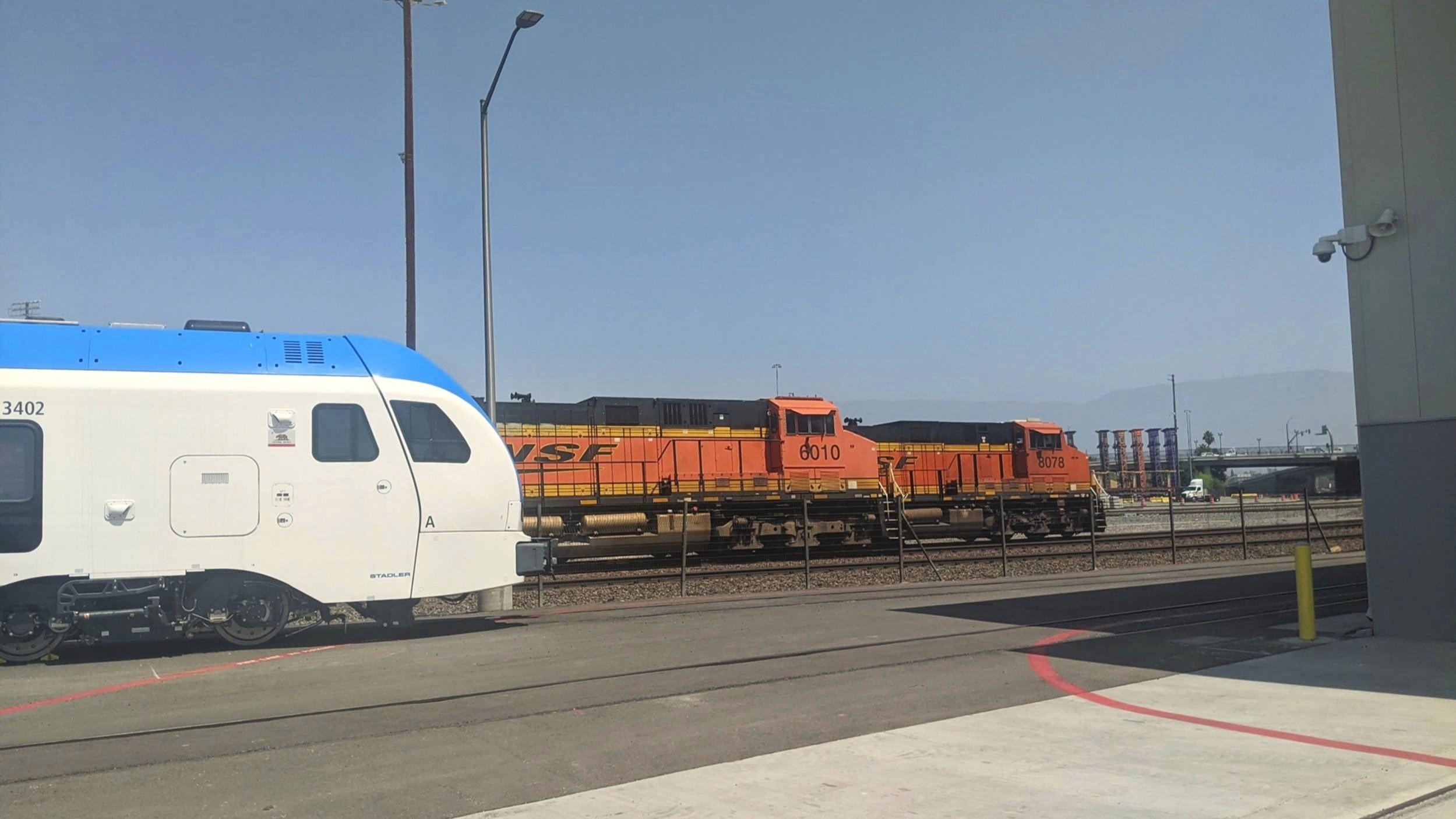  Two BNSF trains heading towards Cajon Pass charge past a brand-new Stadler DMU on the east end of the railyard in San Bernardino, CA. Photo by Alex Lewis, 2022. 