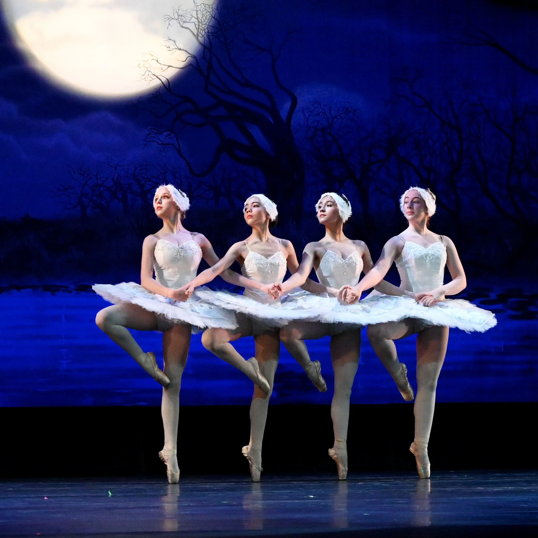Four dancers on stage performing in Swan Lake.