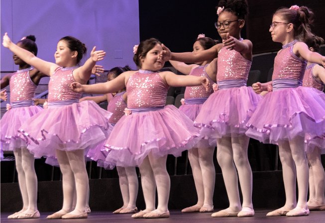 A group of young dancers in costume performing in a recital.