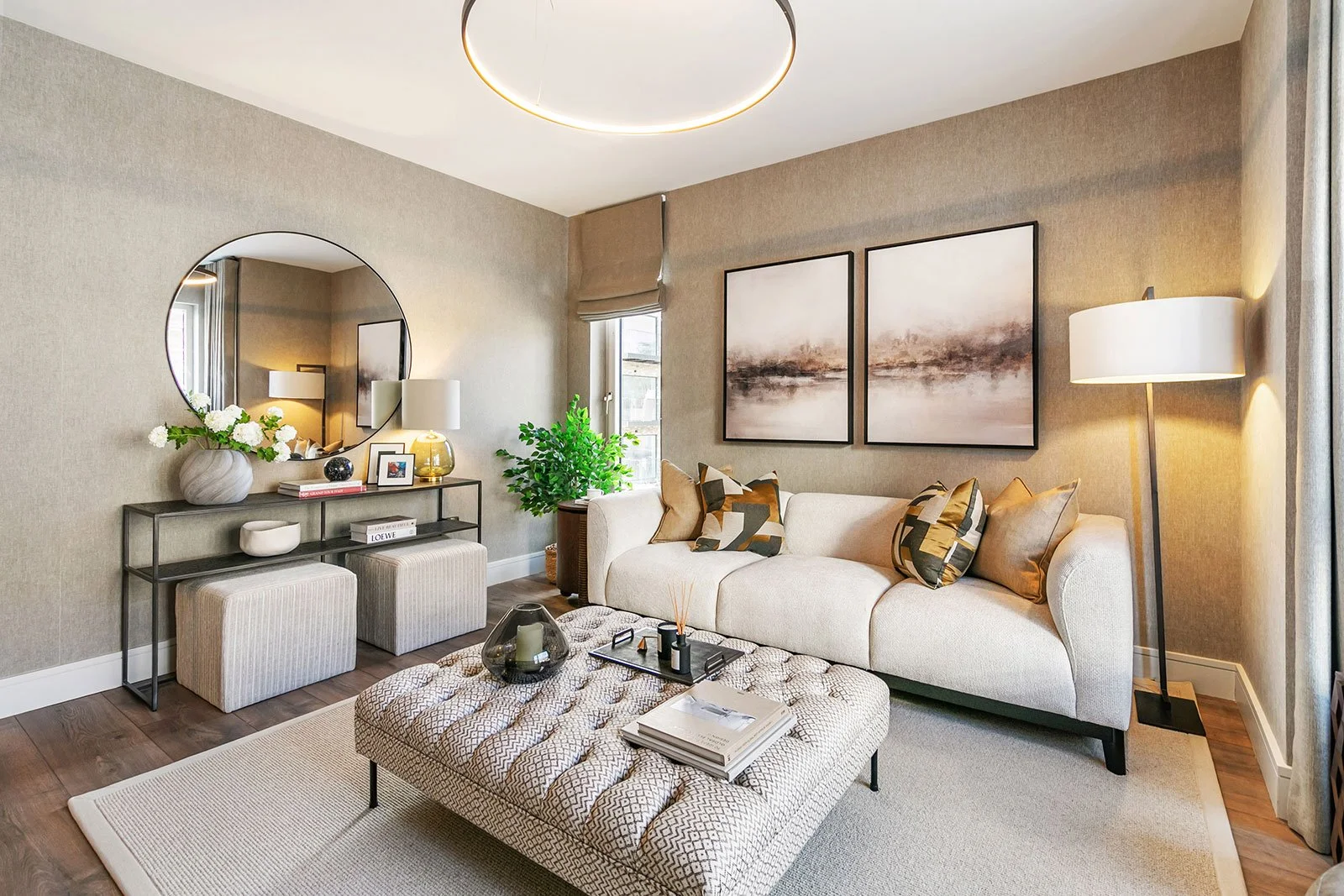Modern sittingroom with neutral decor with off white couch, grey poof, large mirror and area rug