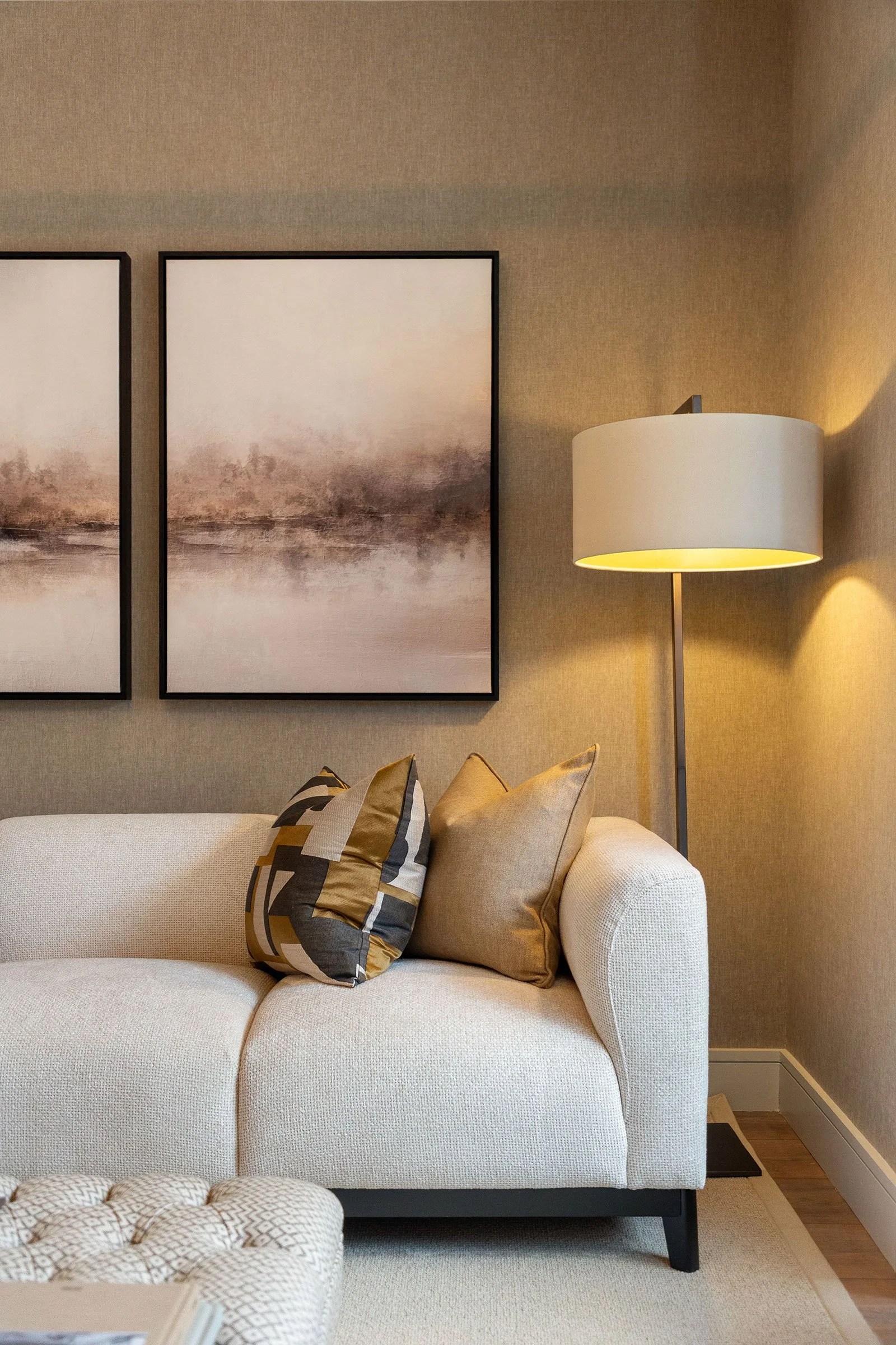 Close up of white sofa with floor lamp and 2 pictures hanging behind