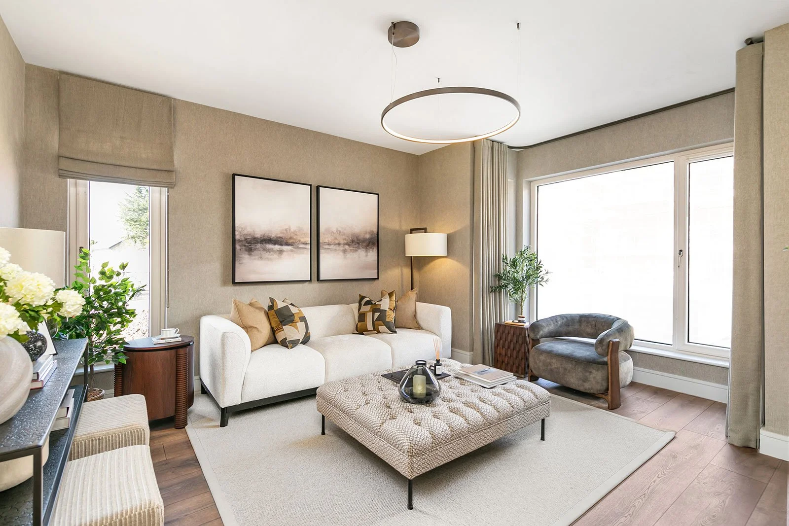 Modern sittingroom in neutral decor with white couch, grey poof and large area rug