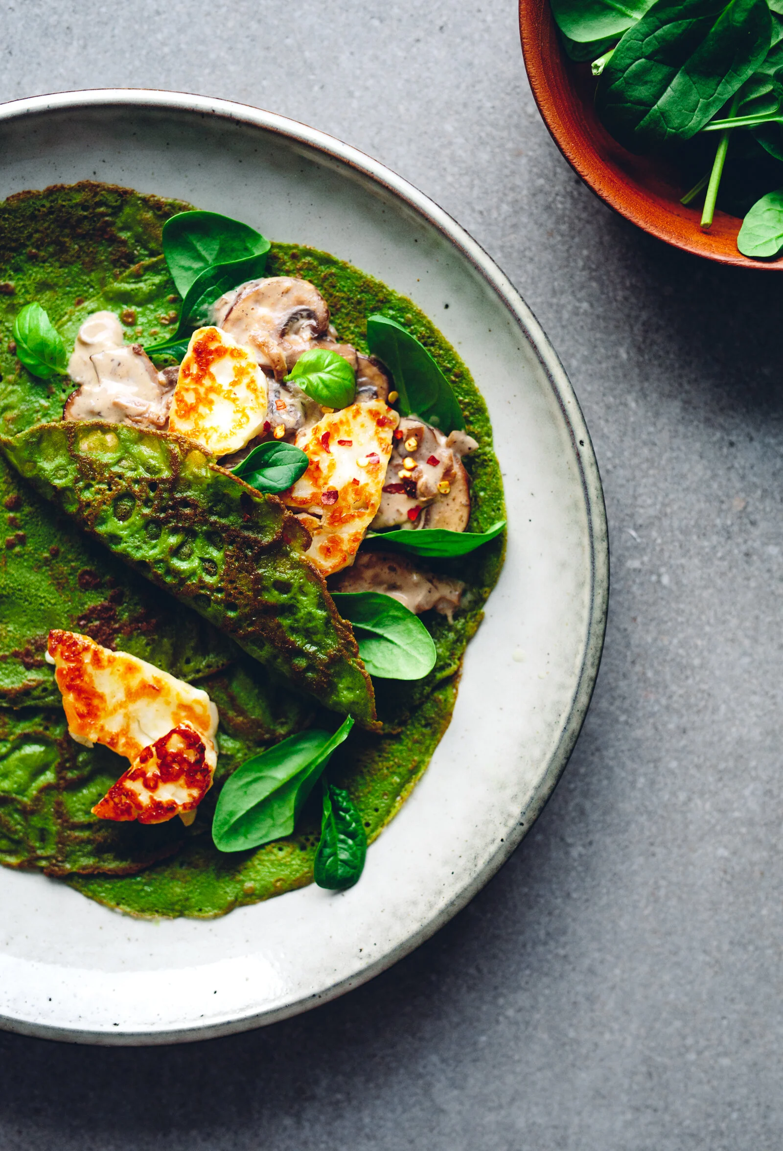 Spenatcrêpes med krämiga skogschampinjoner, vitlök, halloumi och basilika