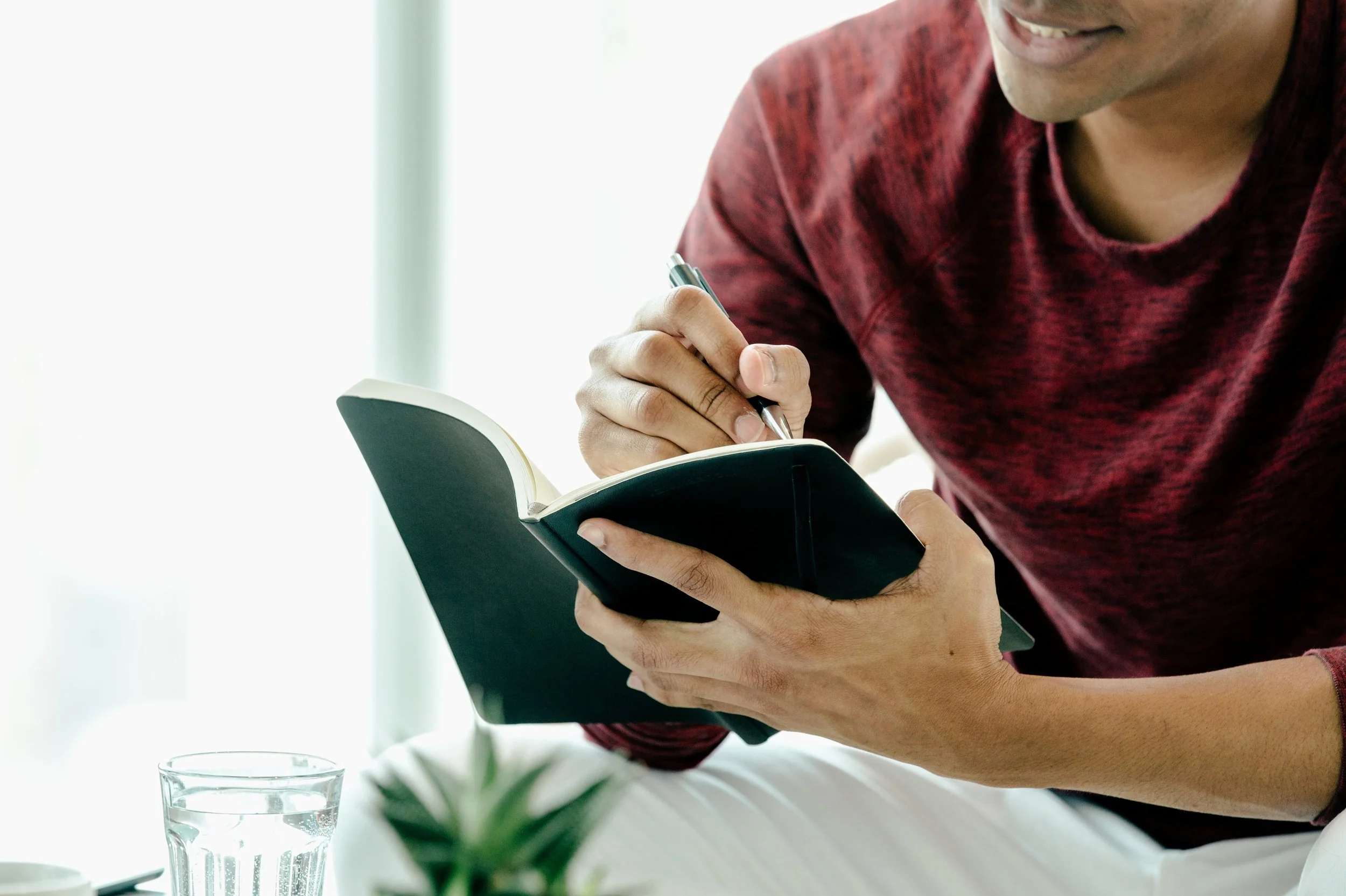 Young man at home writes in a journal.