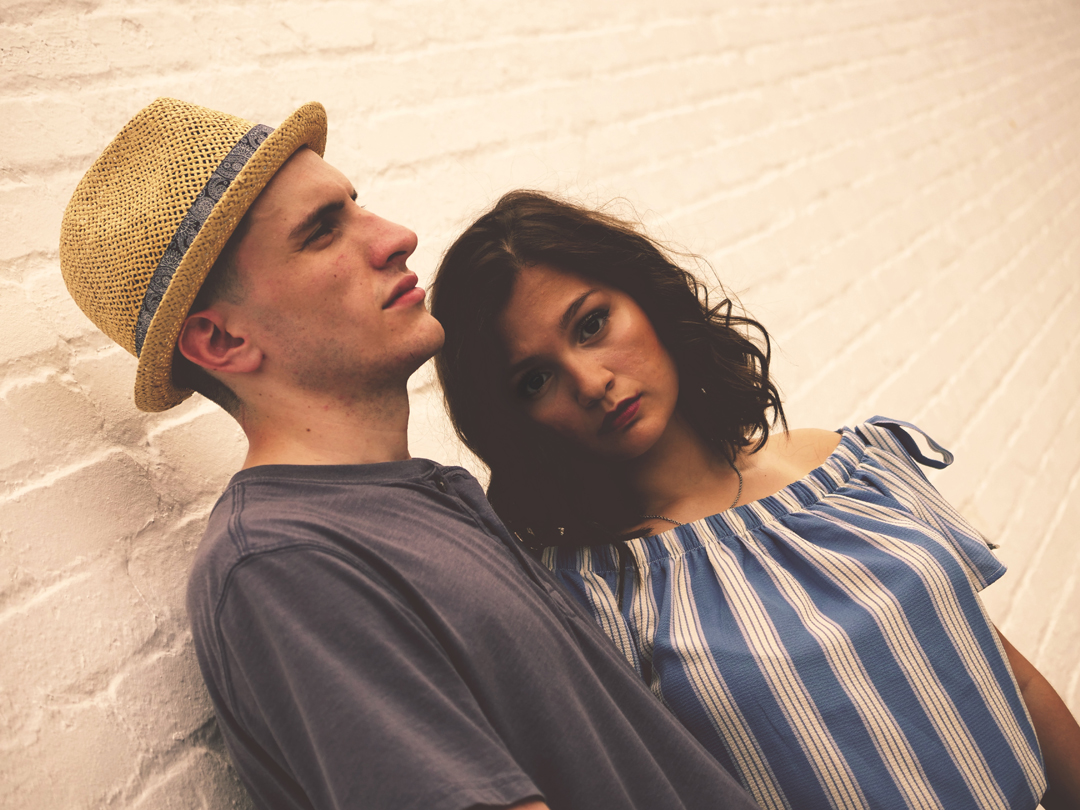 Couple with problems communicating stand against wall in silence.