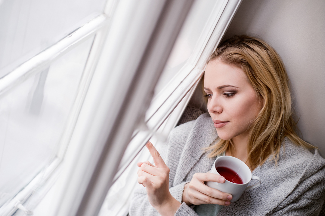 Worried woman stares out of window.