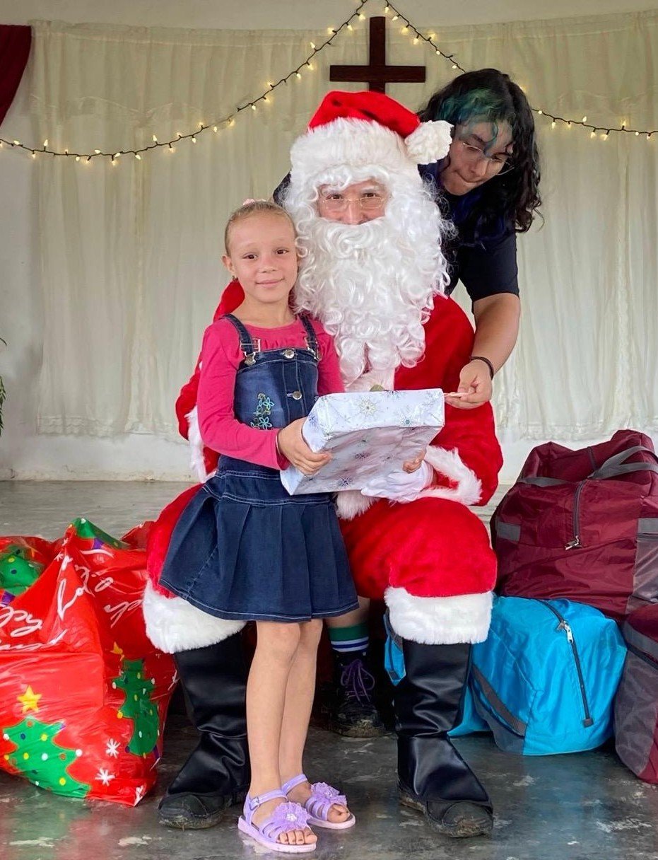 ndrew dressed as Santa Claus delivers a Christmas gift to a child,