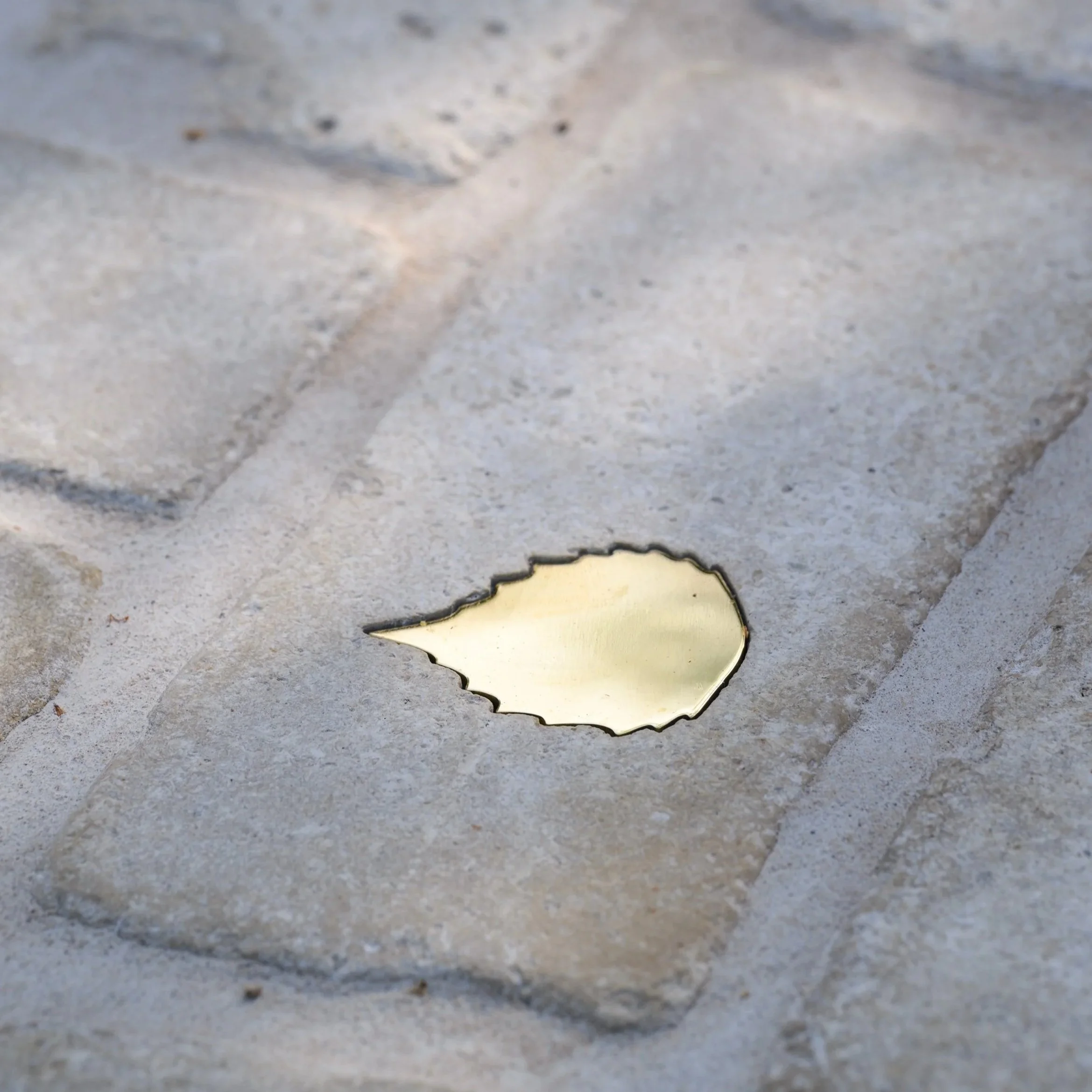 Close-up of a brass leaf countersunk into a limestone cobble.