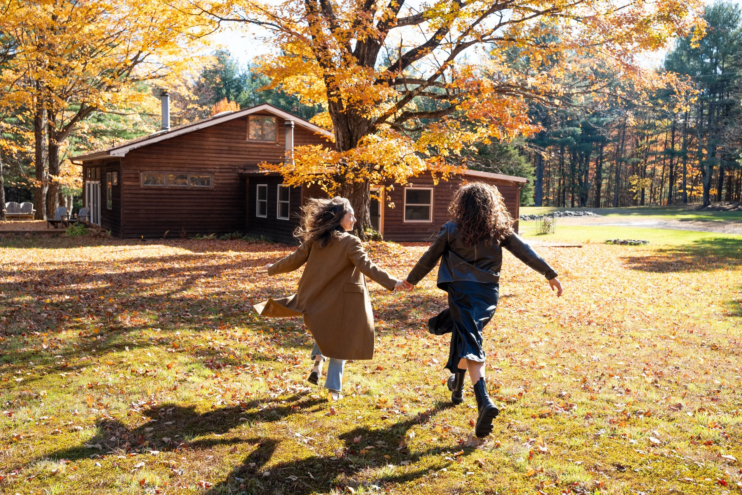 A lesbian couple hold hands in a fall photography scene in the Catskills
