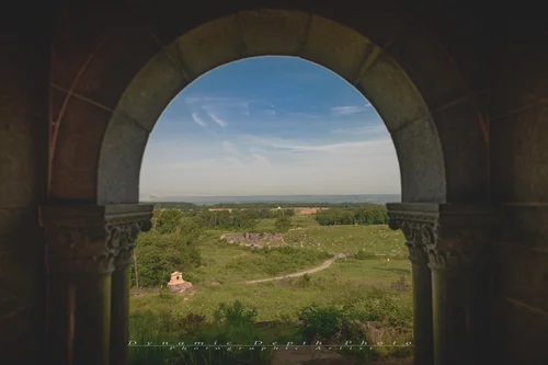 View through a rounded arch of the 12th and 44th New York Infantry Monument toward Devil’s Den and the fields beyond.