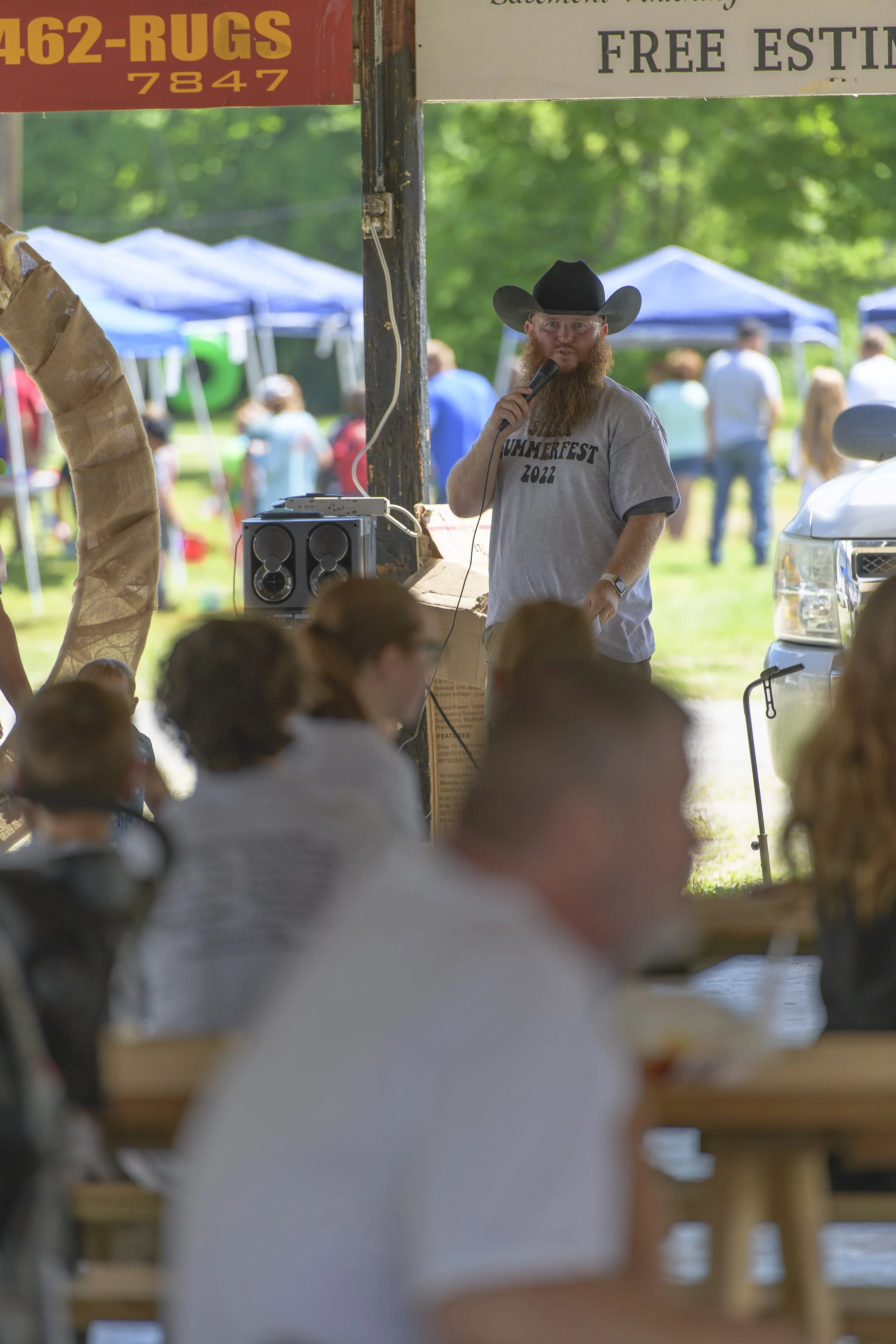A speaker in a black cowboy hat holds a microphone beside the seated crowd at the 2022 Silex Festival.