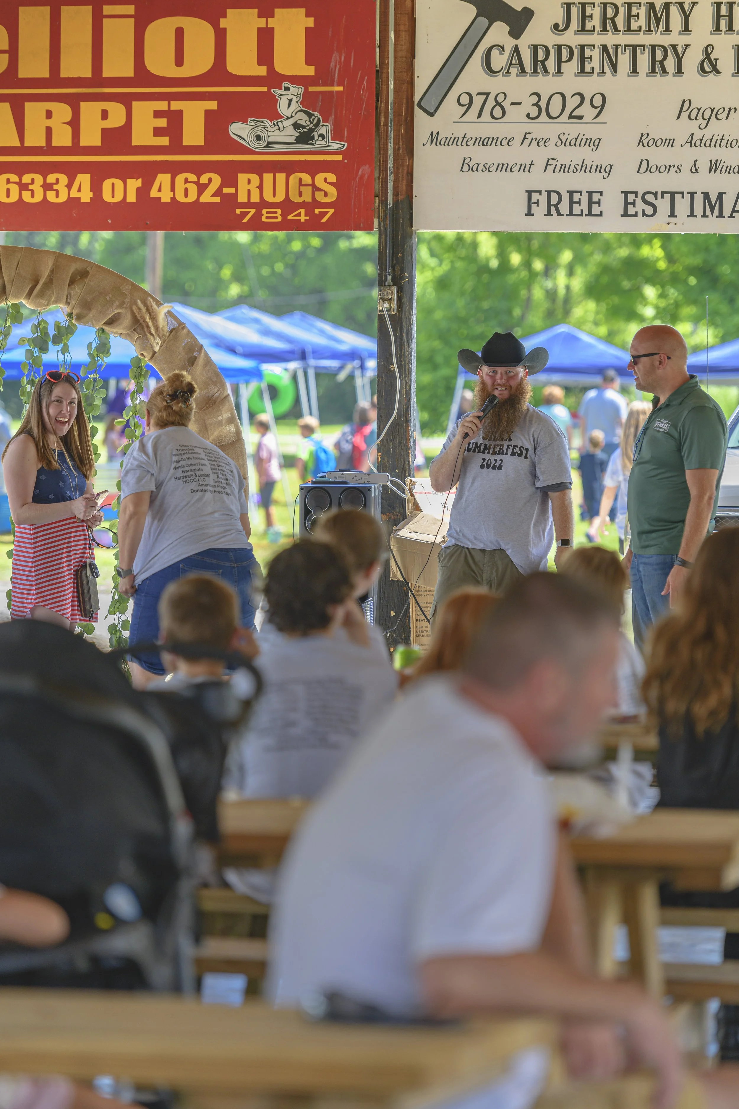 Attendees sit at picnic tables beneath the festival pavilion at the 2022 Silex Festival.