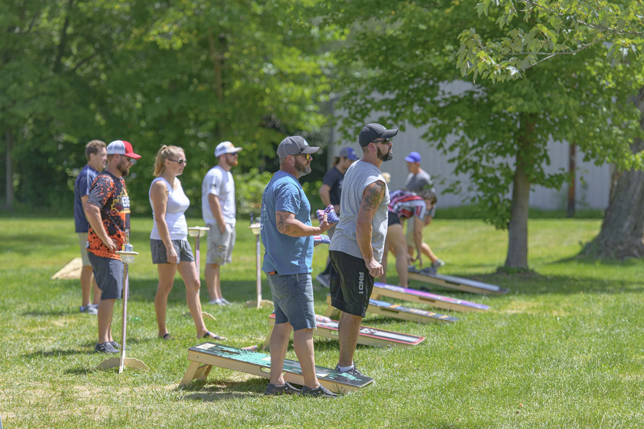 Cornhole players stand beside rows of boards on the grass at the 2022 Silex Festival.