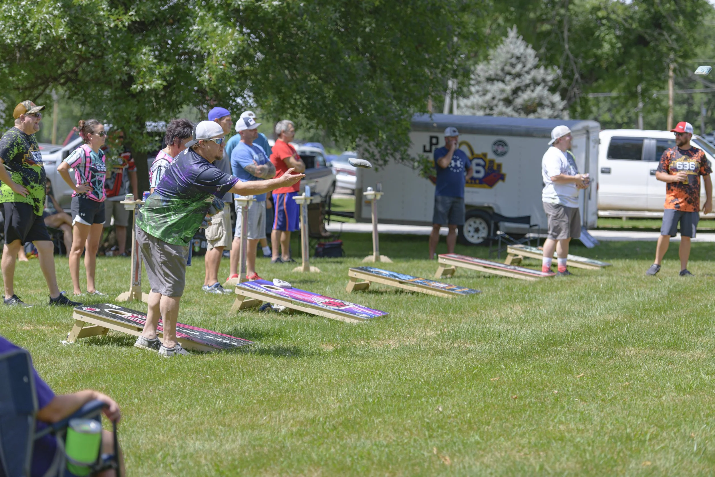 A player releases a beanbag with other games continuing behind him at the 2022 Silex Festival.