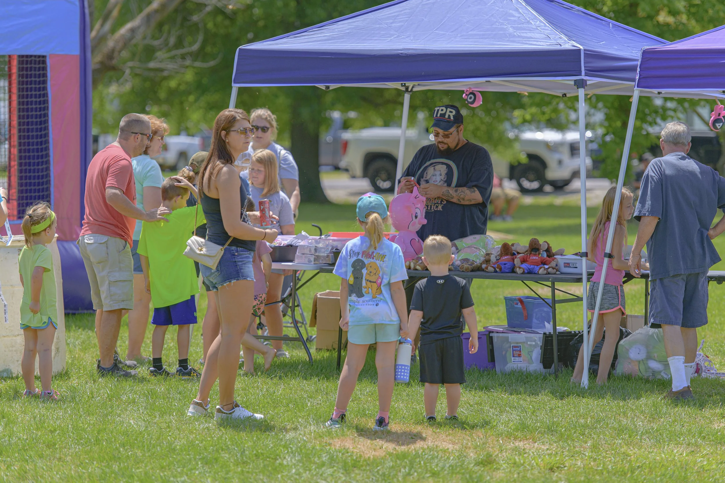 Adults and children visit an activity table beneath a blue canopy at the 2022 Silex Festival.