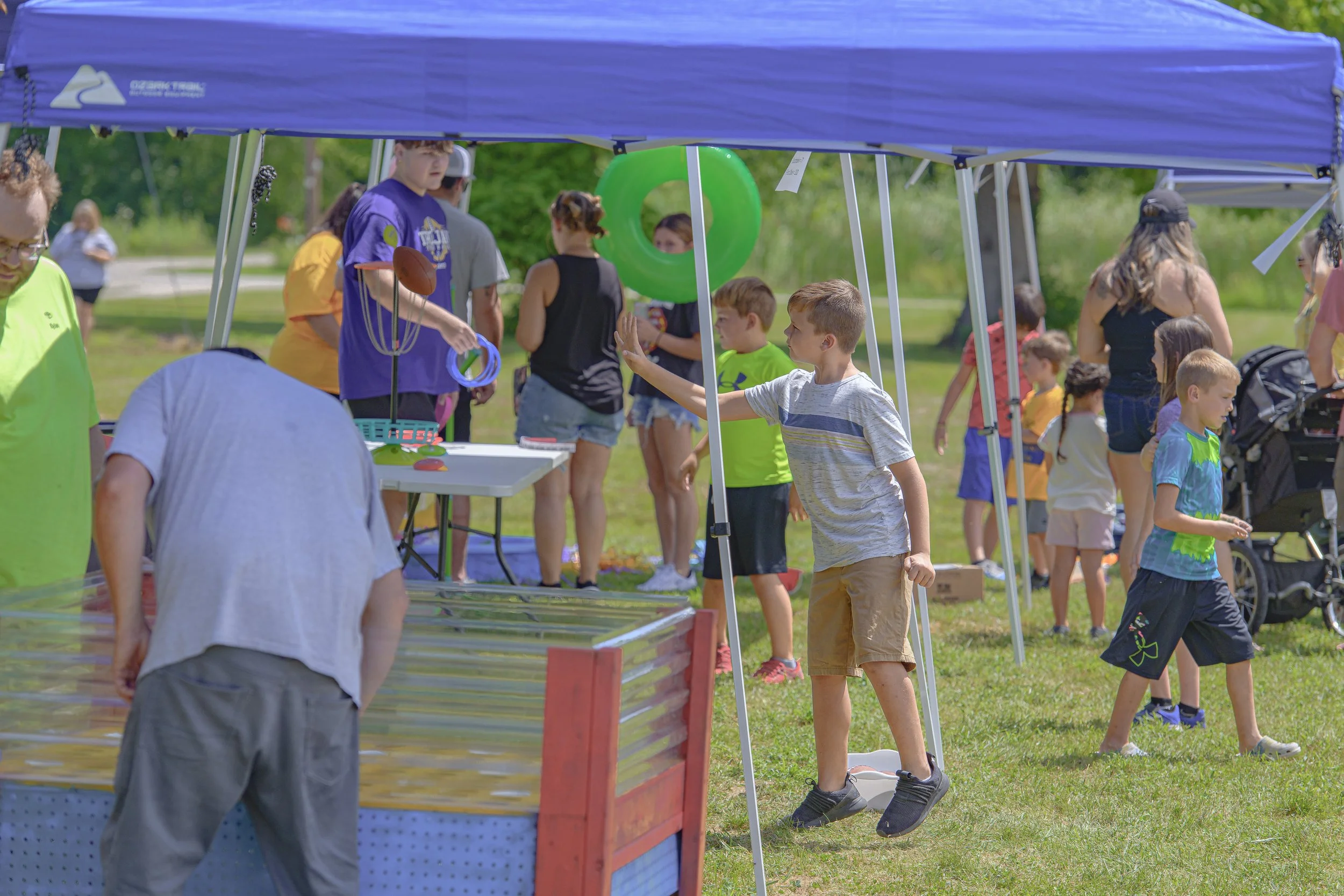Children and adults gather around an activity beneath a blue canopy at the 2022 Silex Festival.