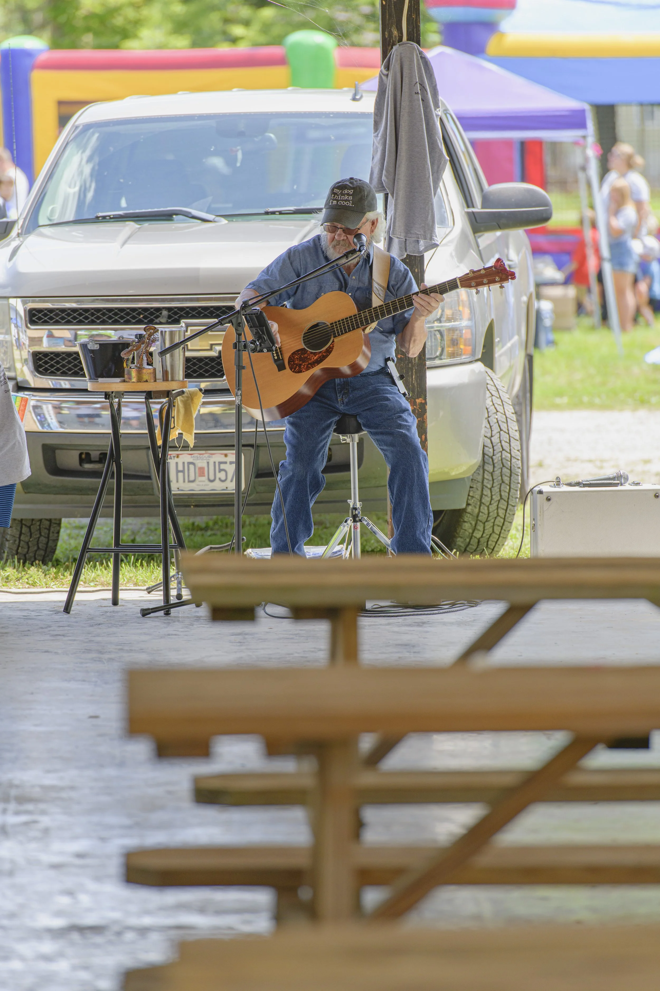 A seated guitarist performs beside the pavilion, with picnic tables in the foreground at the 2022 Silex Festival.