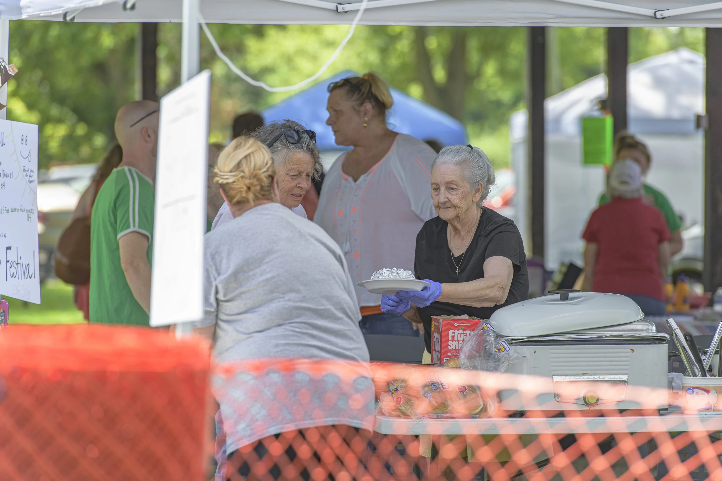 People work behind a serving table beneath a canopy at the 2022 Silex Festival.