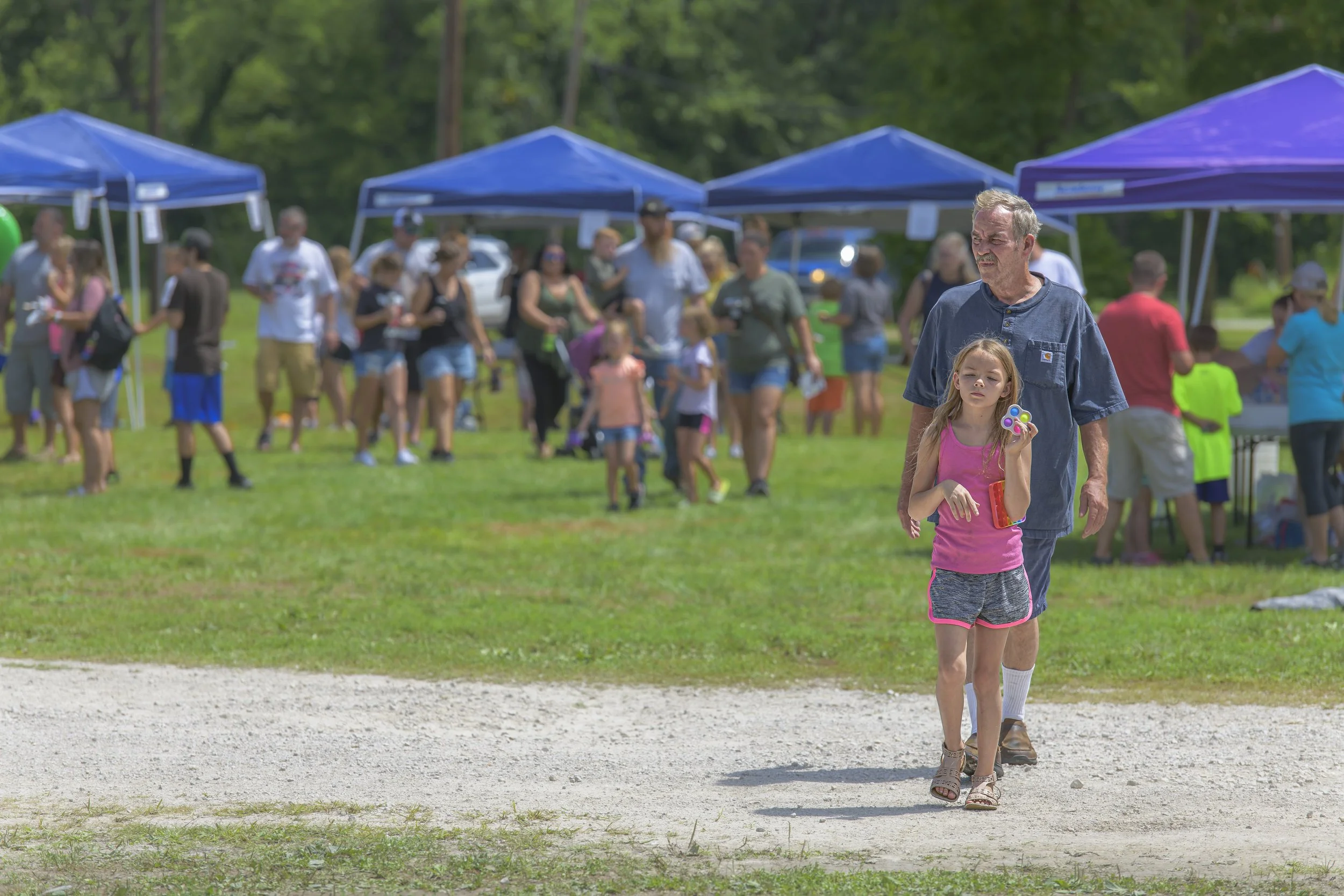 A child crosses the gravel path with an adult following from the festival grounds at the 2022 Silex Festival.