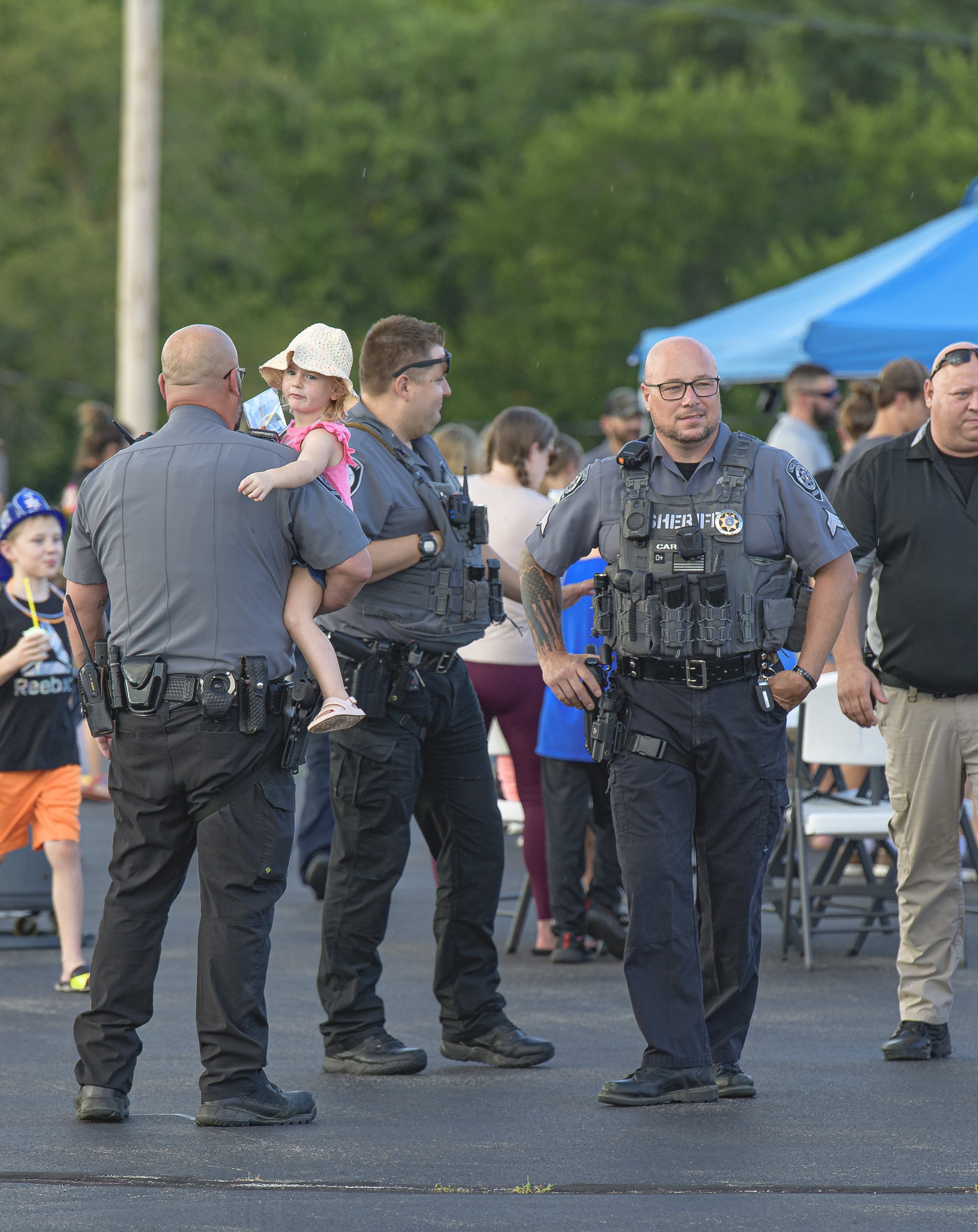 Uniformed officers stand among attendees near an event canopy at the 2022 National Night Out.