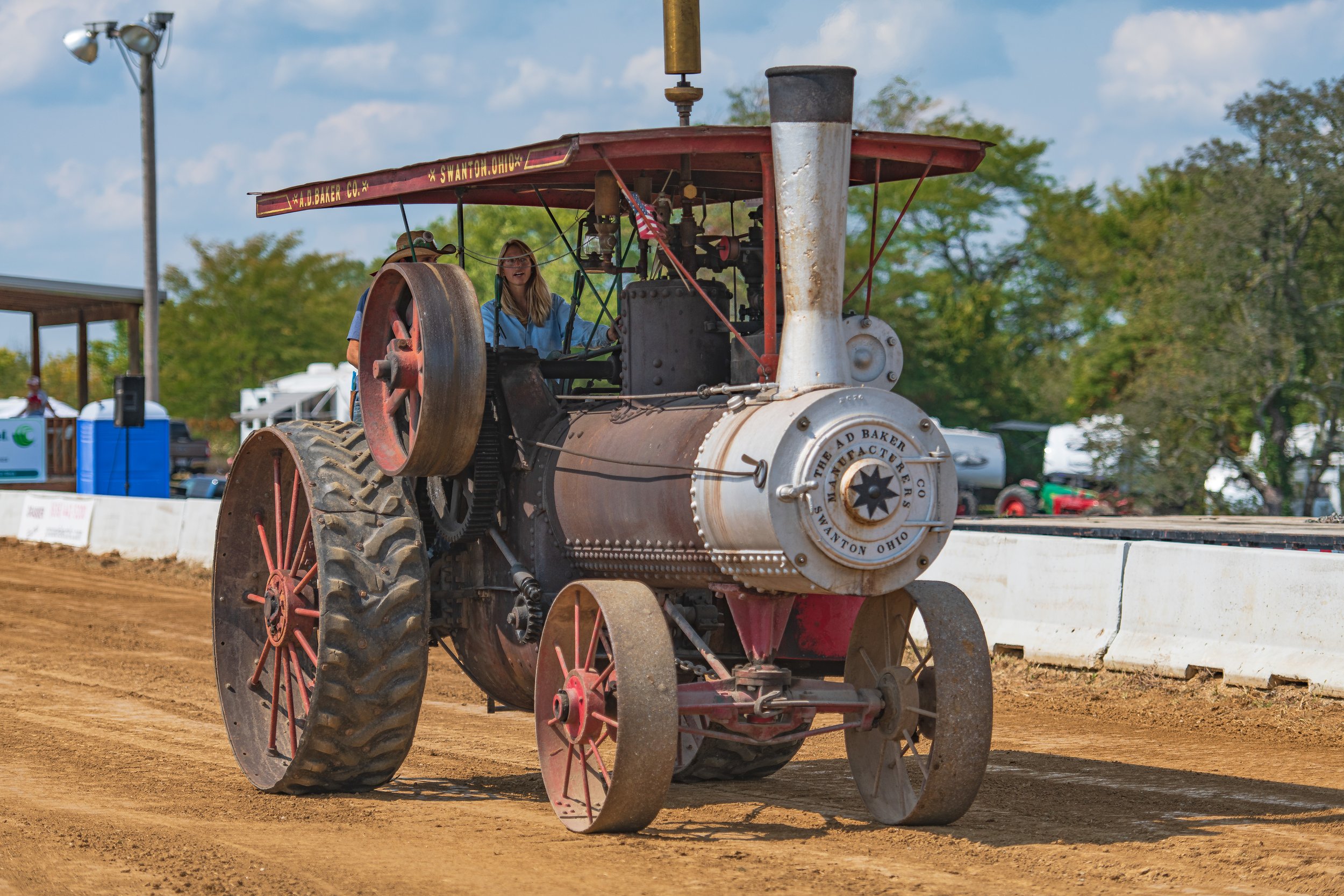 A steam traction engine approaches the camera, showing its tall smokestack and round metal front at the 2022 Old Thresher Days.